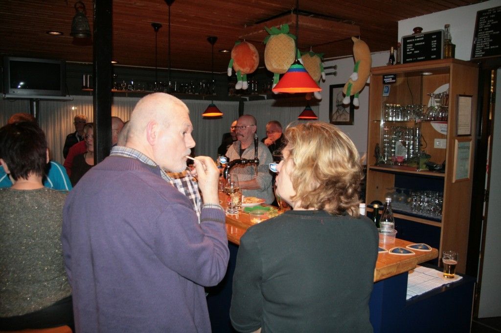 Mensen die gezellig samen zijn in een bar met decoratieve hanglampen en een houten boekenkast op de achtergrond.