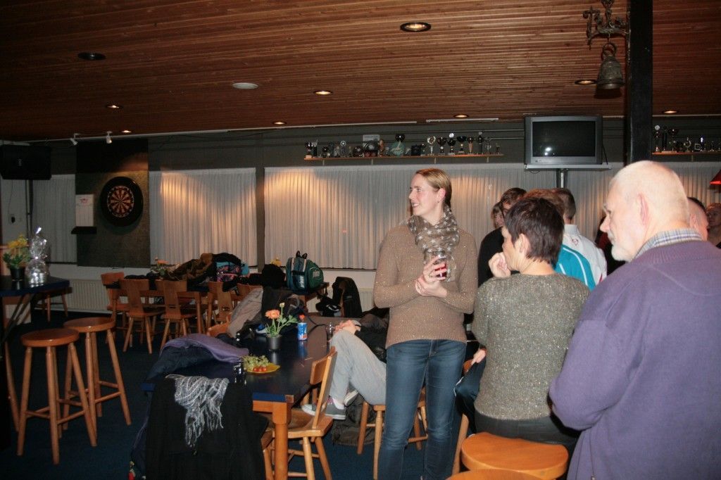 Mensen verzamelen zich in een schemerig verlichte bar met een dartbord aan de muur