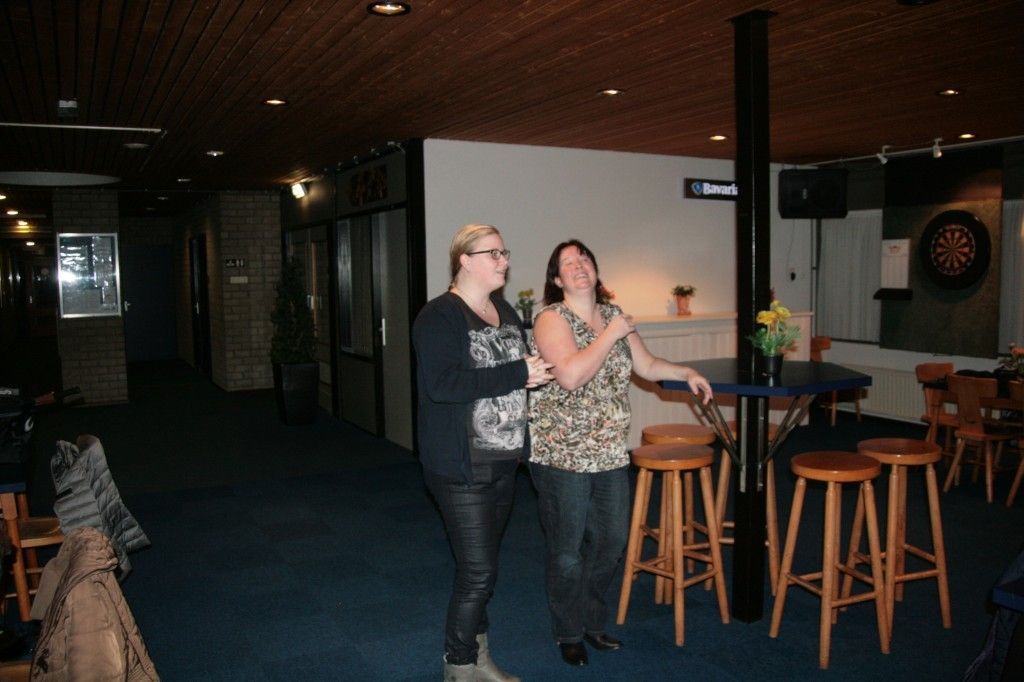 Twee mensen staan ​​te glimlachen in een schemerig, met tapijt bekleed café- of loungegedeelte