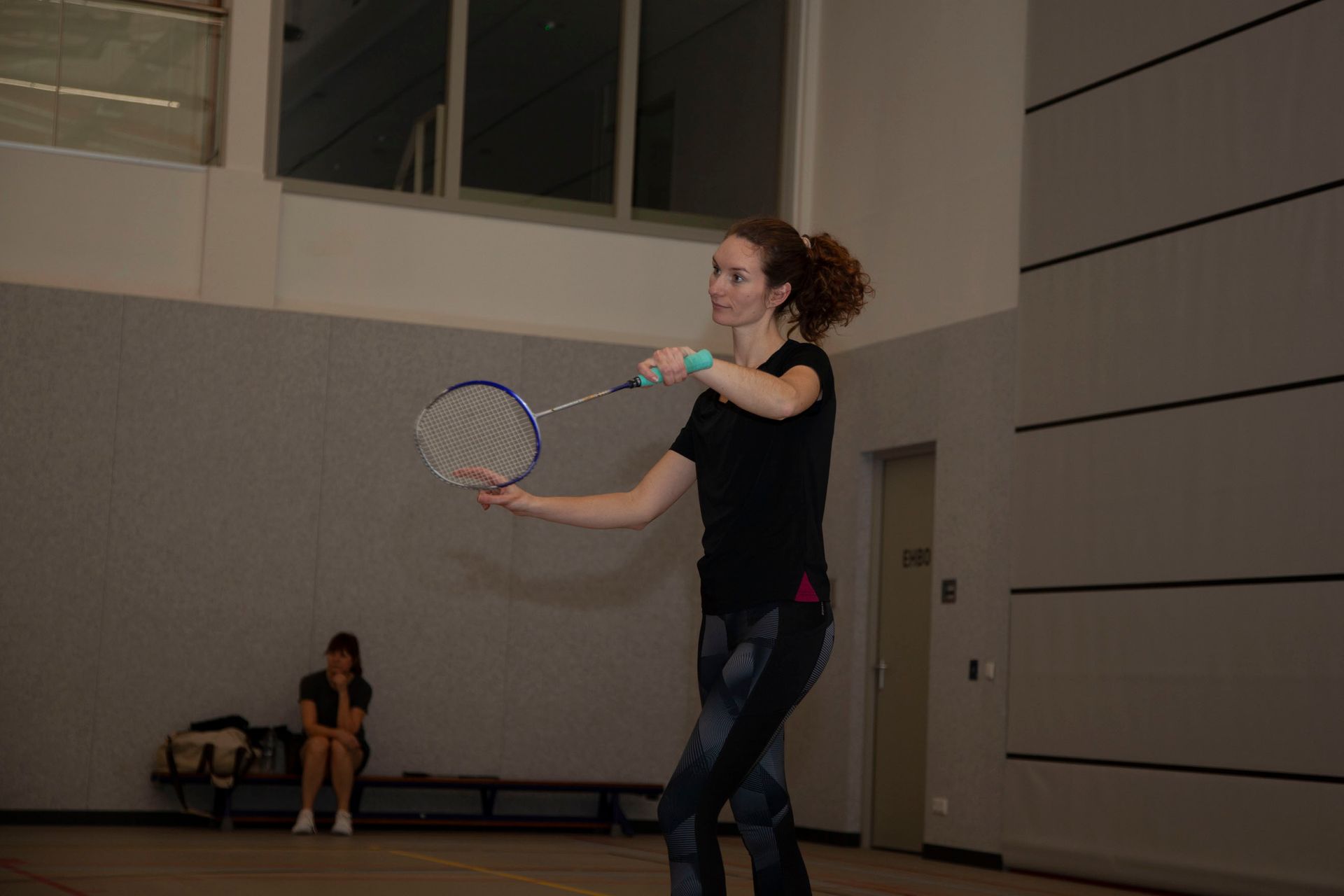 Een persoon houdt een badmintonracket vast in een starthouding