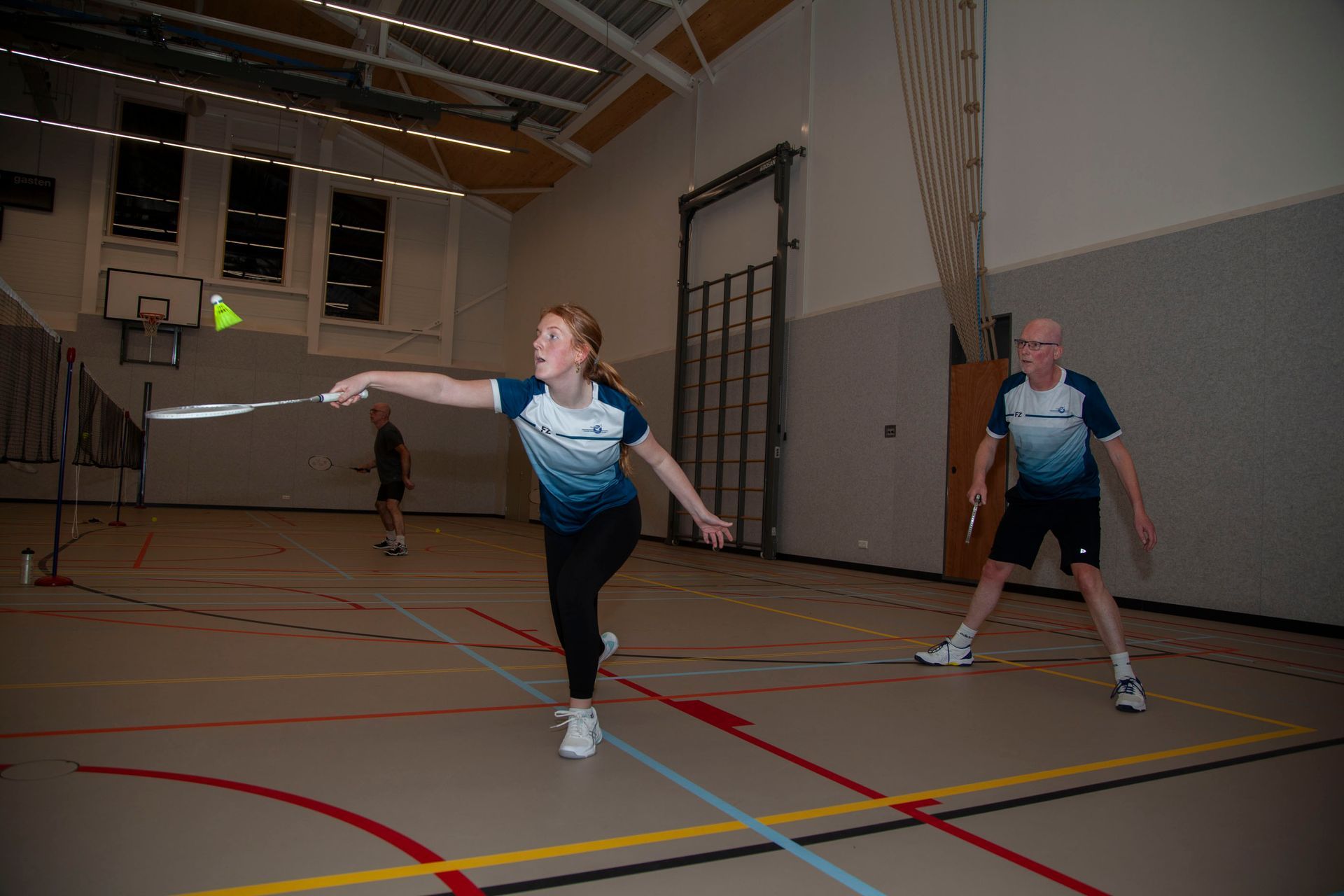Twee mensen in blauw-witte sportkleding spelen badminton