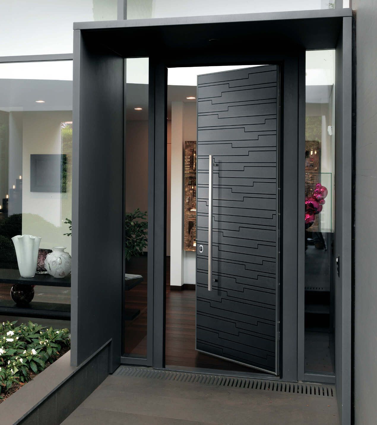 Porta d'ingresso nera con design testurizzato, maniglia in acciaio inox, aperta. Ingresso di casa moderno.