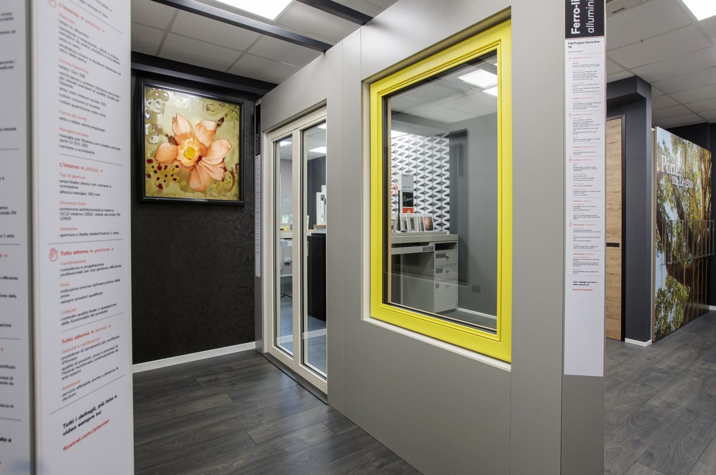 Esposizione di vetrine e porte nello showroom con finestra con cornice gialla, porta scorrevole e opere d'arte.