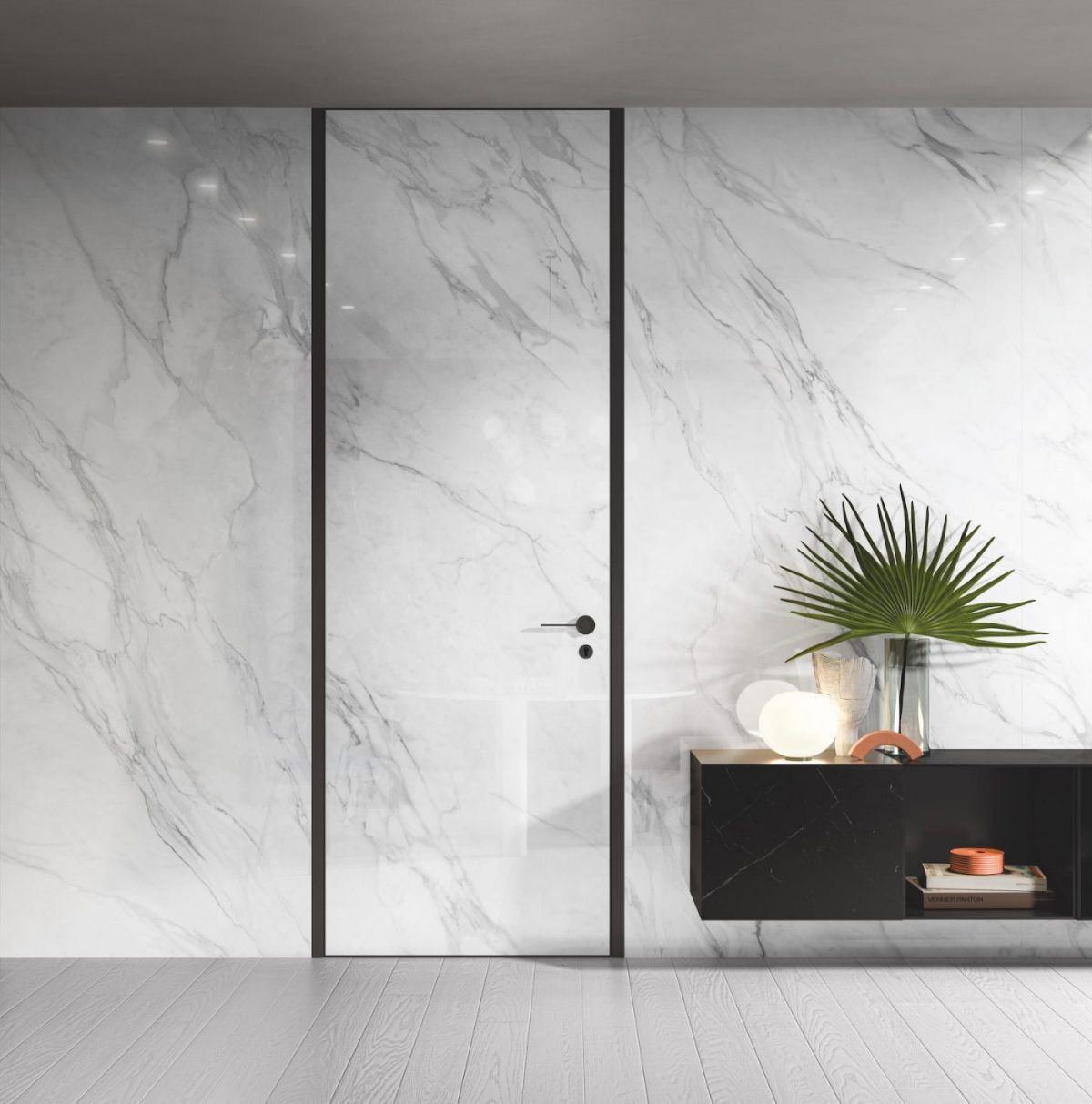 Parete in marmo bianco con porta con finiture nere e mobiletto nero sospeso con piante.