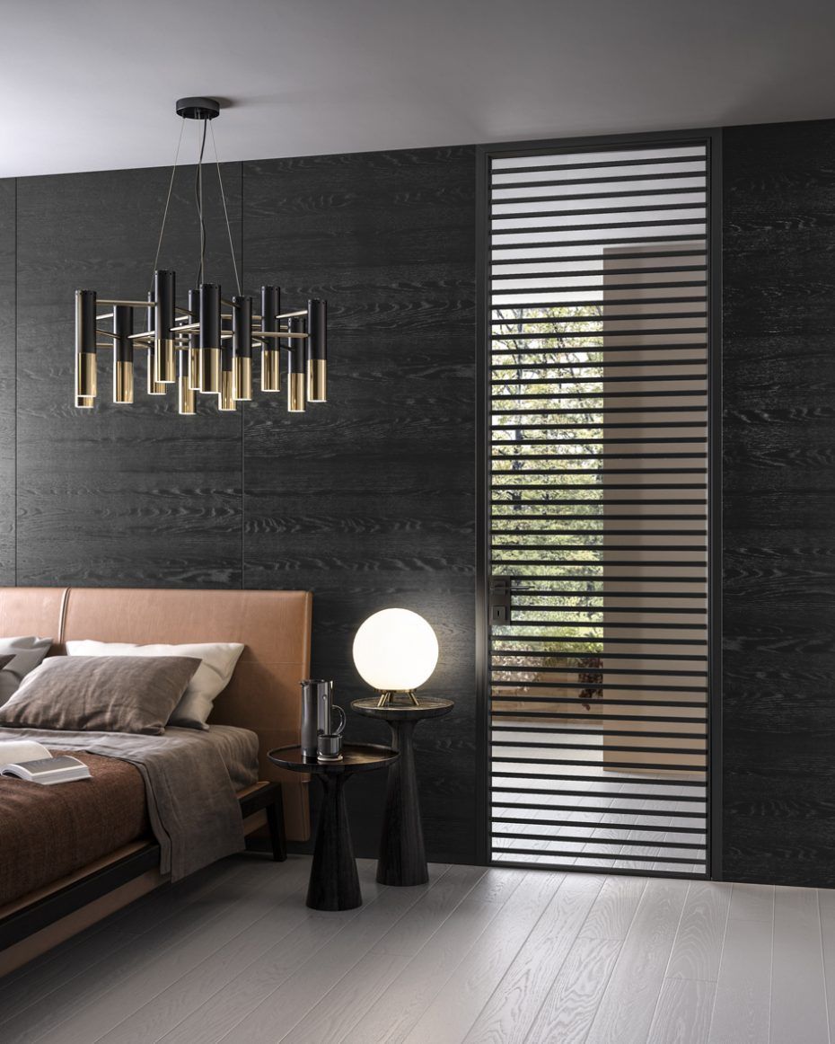Camera da letto con parete scura, letto, lampadario moderno, tavolino con lampada e pannello della finestra a doghe.
