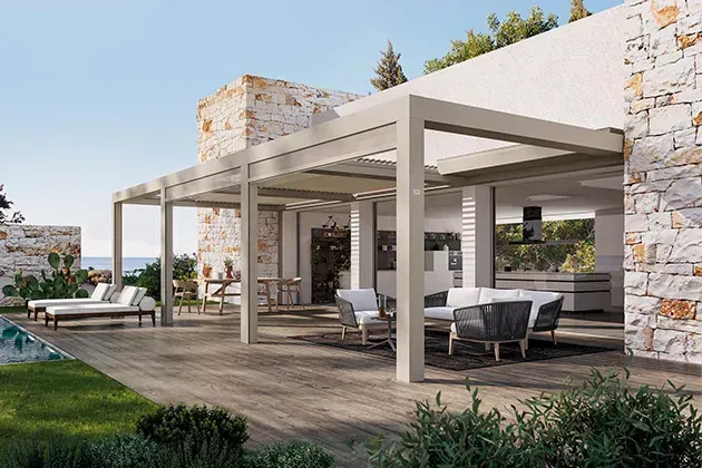Patio esterno con pergolato moderno, terrazza in legno, mobili, piscina e muro in pietra.