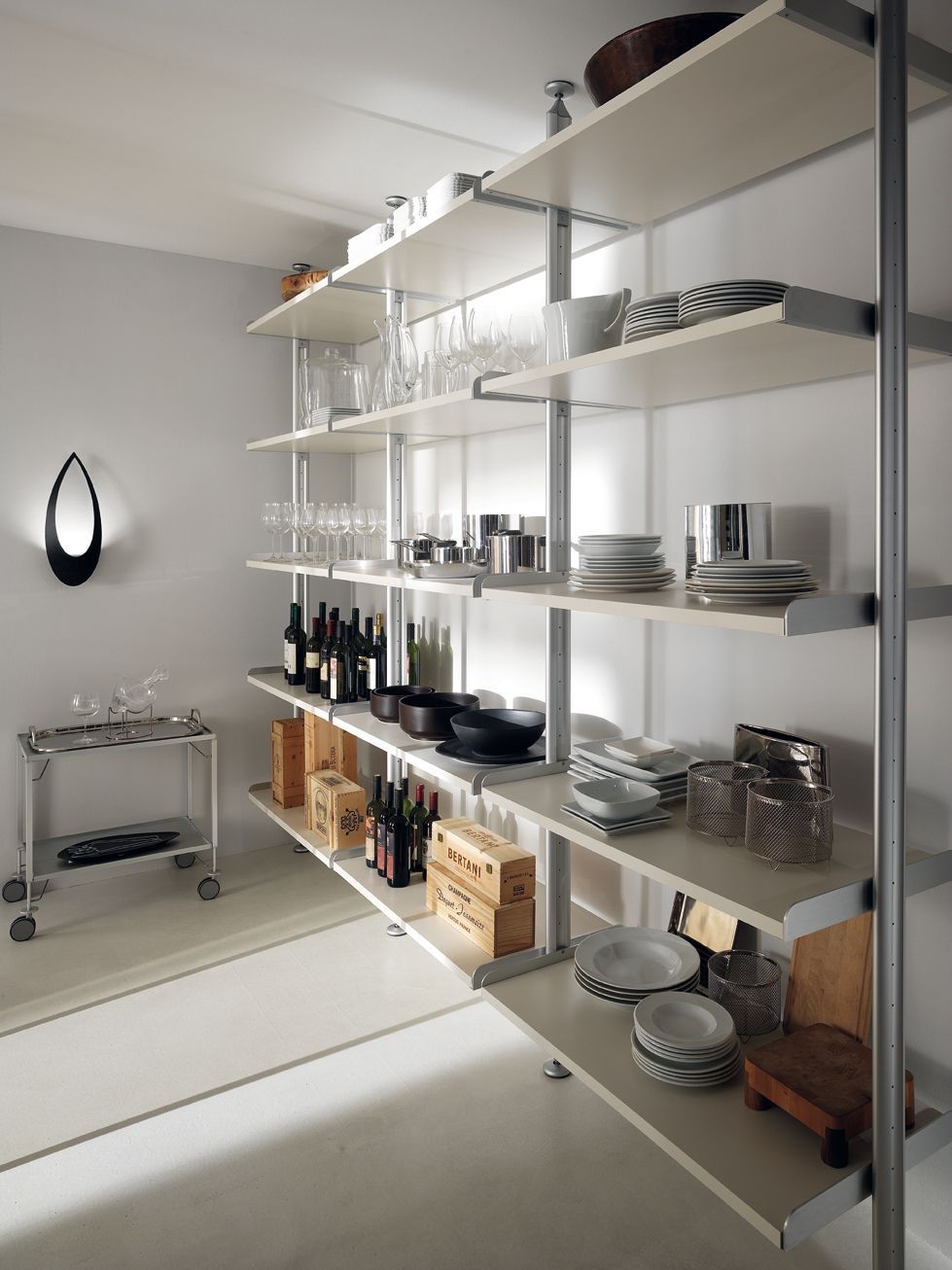 Scaffale bianco in una dispensa piena di piatti, bicchieri e generi alimentari.