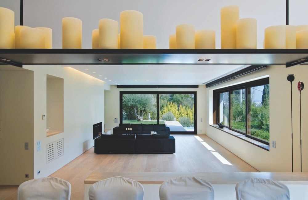 Soggiorno moderno con finestre con cornice nera, divano nero, candele su uno scaffale.