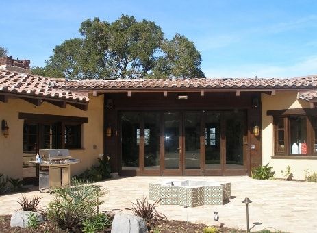 Patio con camino, griglia e porte in vetro; pareti beige e tetto marrone.