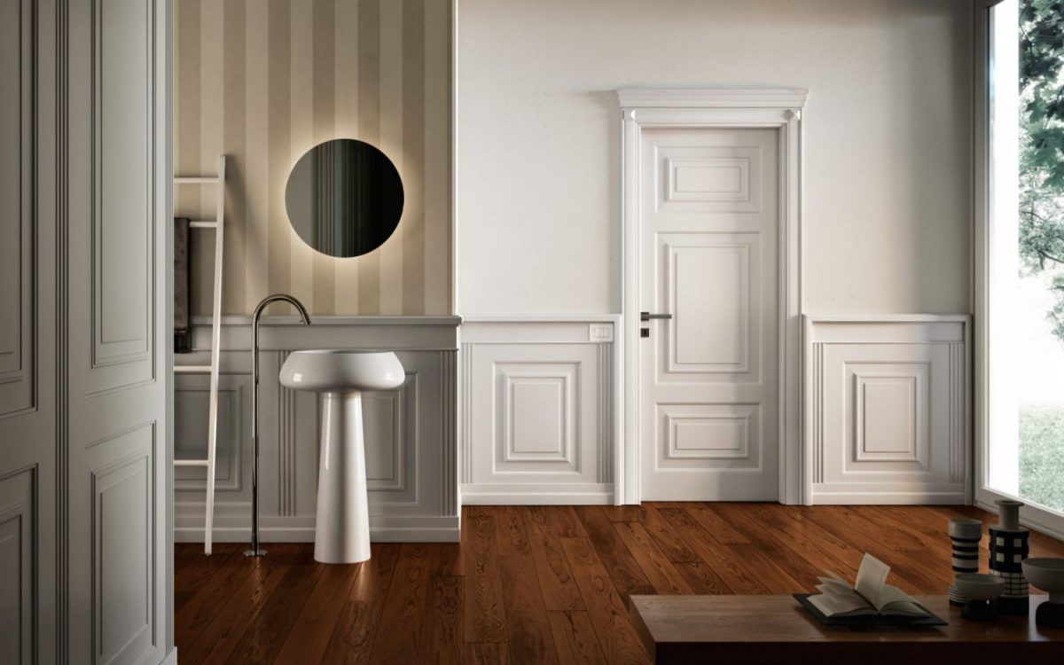 Interni eleganti con pavimento in legno, pareti rivestite di pannelli bianchi, lavabo su piedistallo.