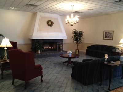 Cozy lounge with white fireplace, red chairs, dark sofa, coffee table, and chandelier