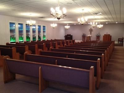 Empty church sanctuary with wooden pews, chandeliers, and a pulpit at the front