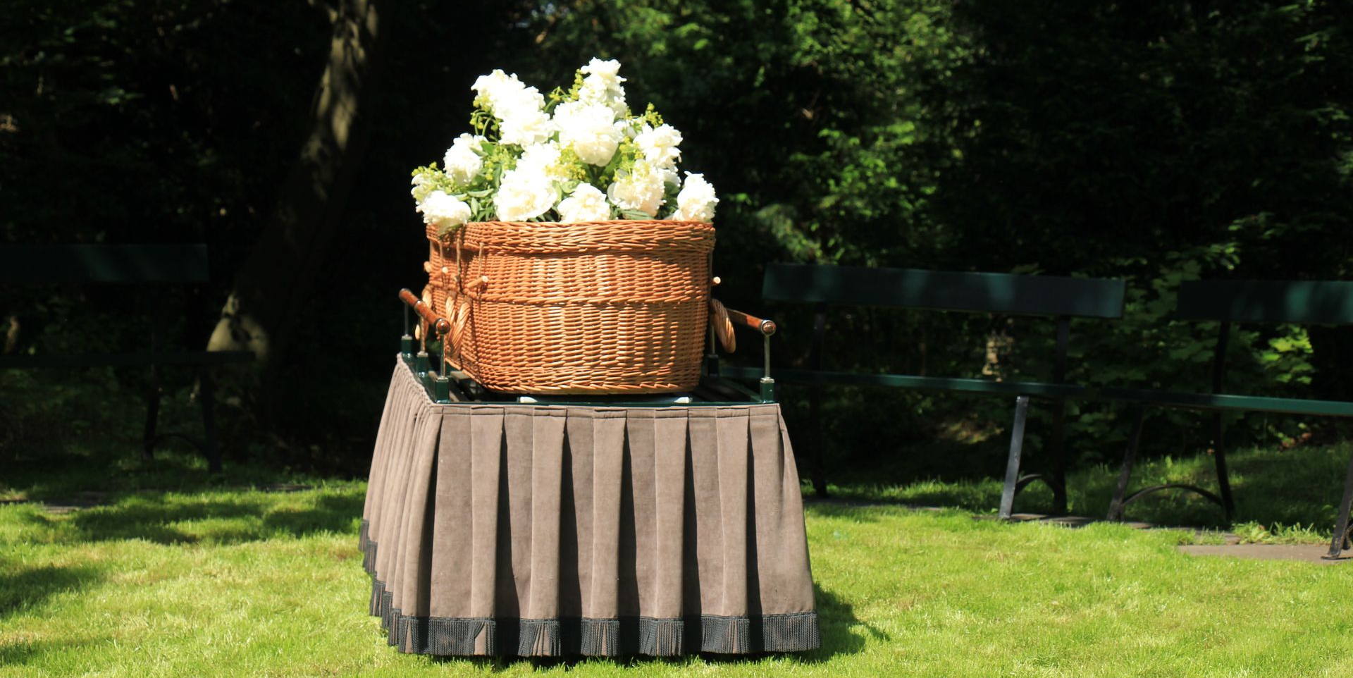 Gloved hand holding a glass-doored casket beside a black suit in a church aisle
