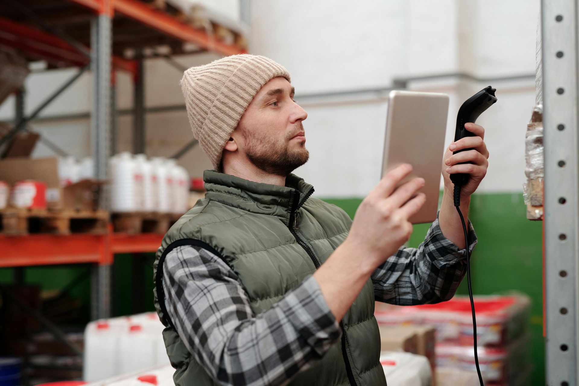 Man in warehouse scanning with tablet and barcode scanner.