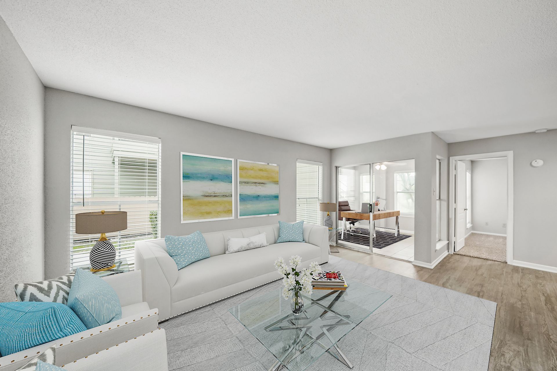 A living room with a white couch and a glass coffee table.