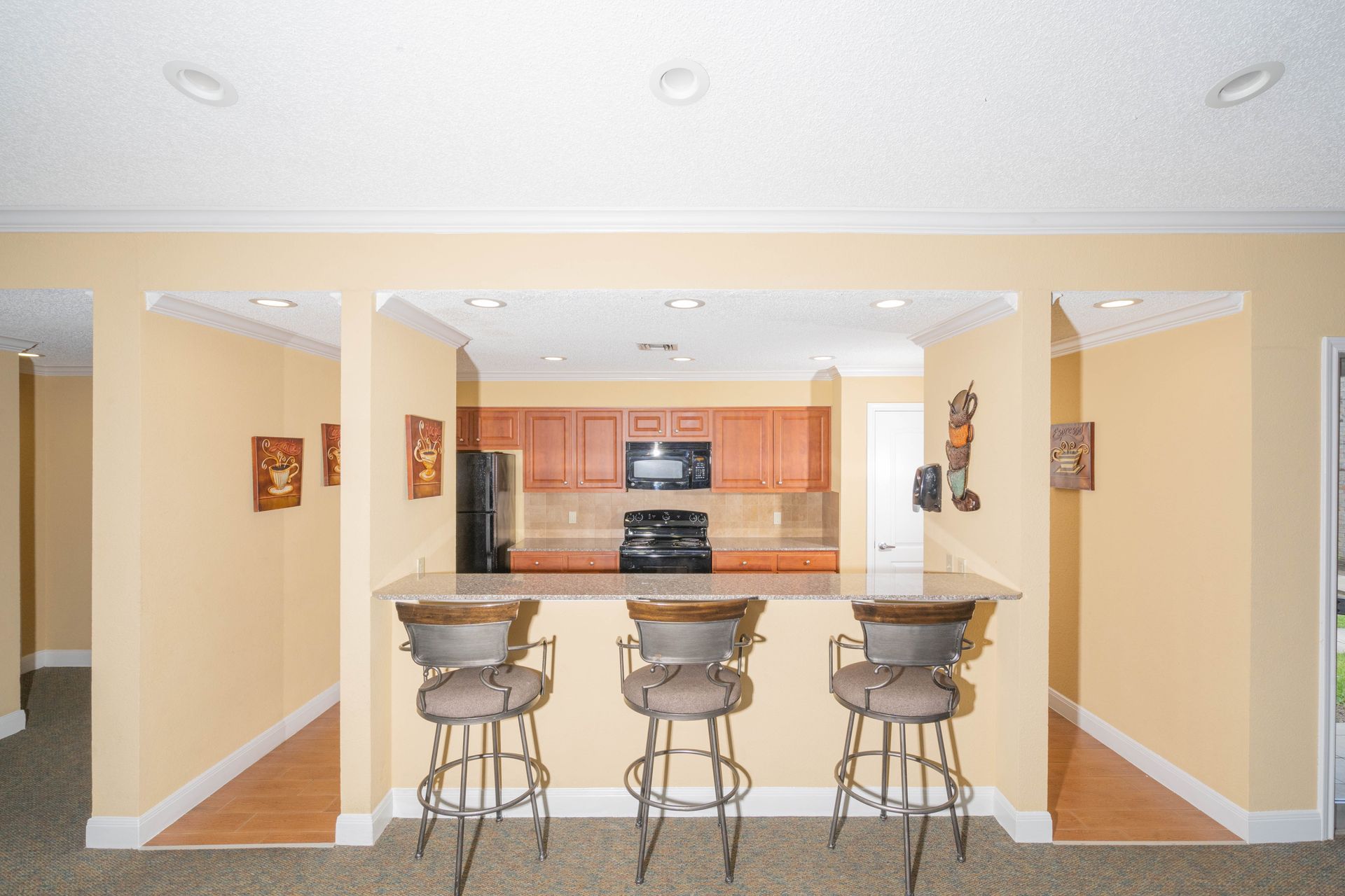 A kitchen with three bar stools and a refrigerator.