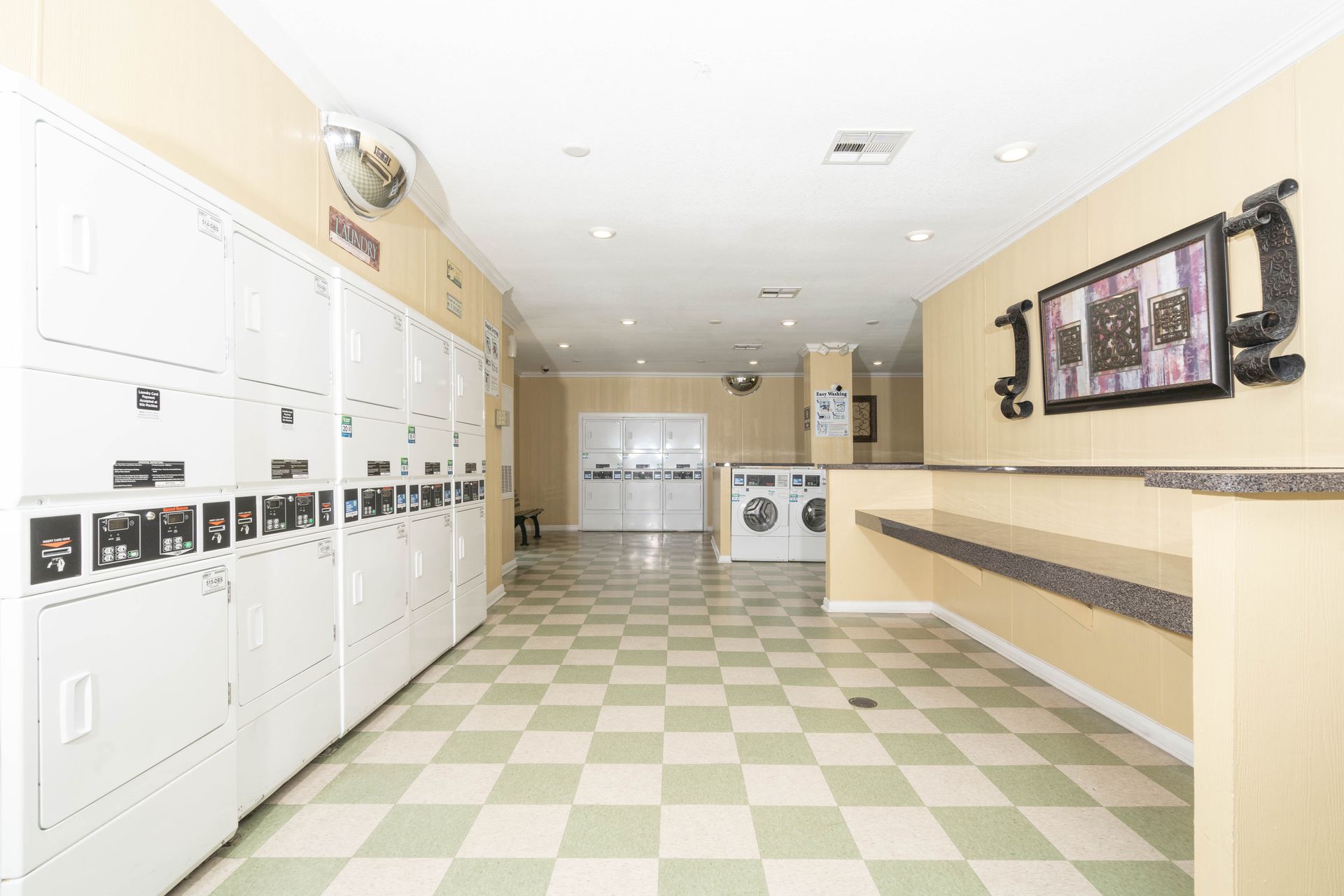 A laundromat with lots of washers and dryers and a checkered floor.