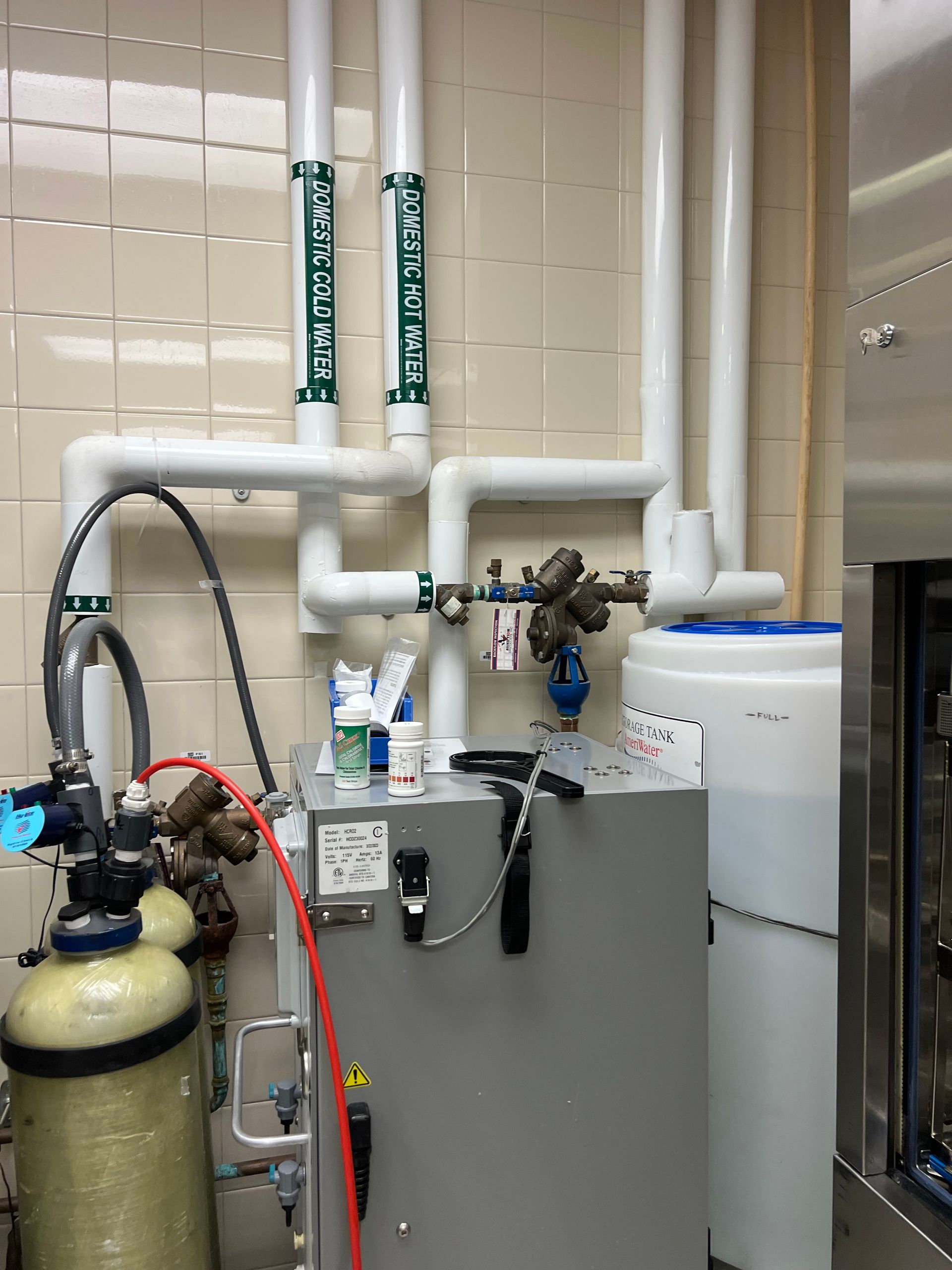 Technician in protective gear operates a machine in a clean industrial lab.
