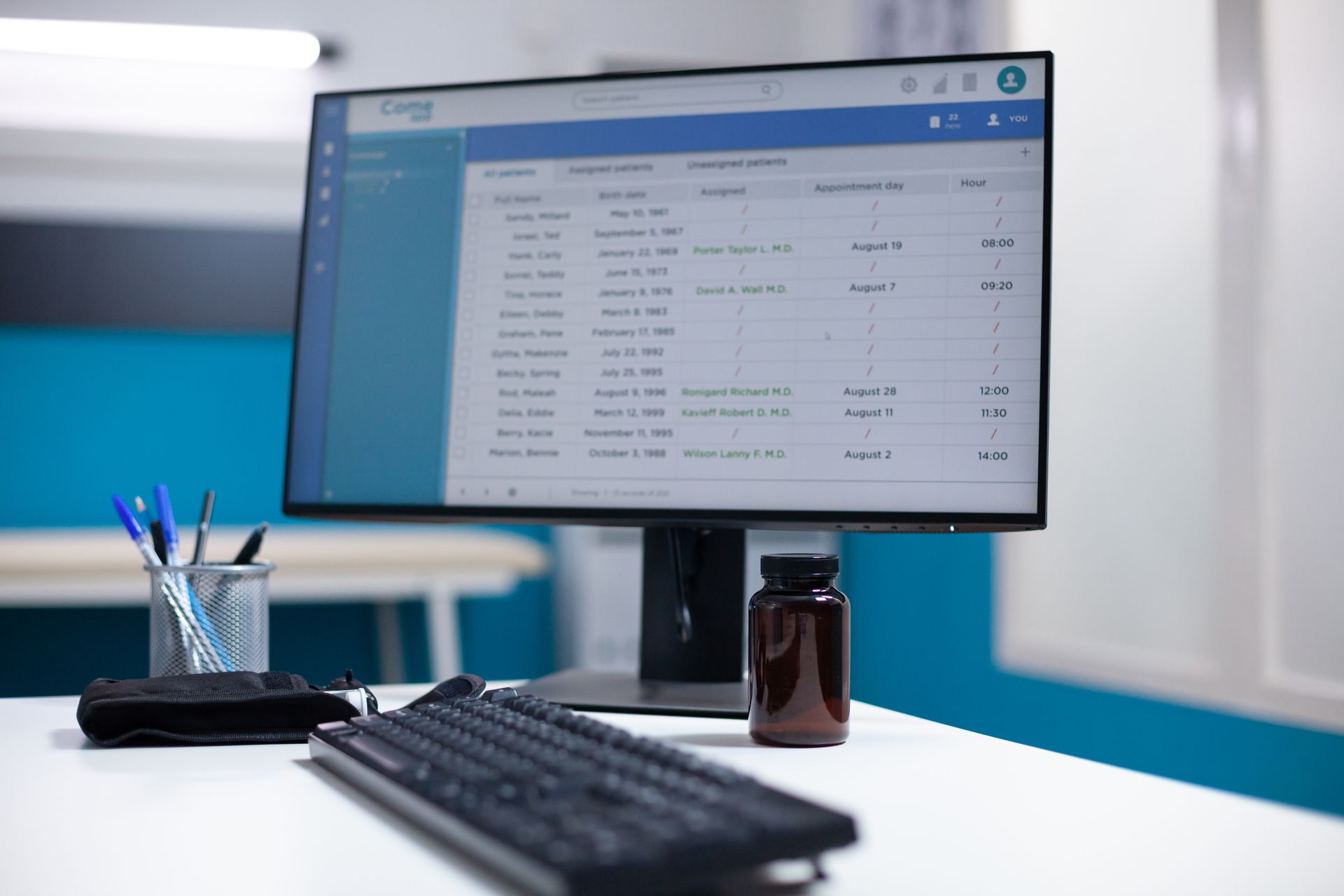 Modern office desk with widescreen monitor, keyboard, pen cup, and coffee mug on a white table