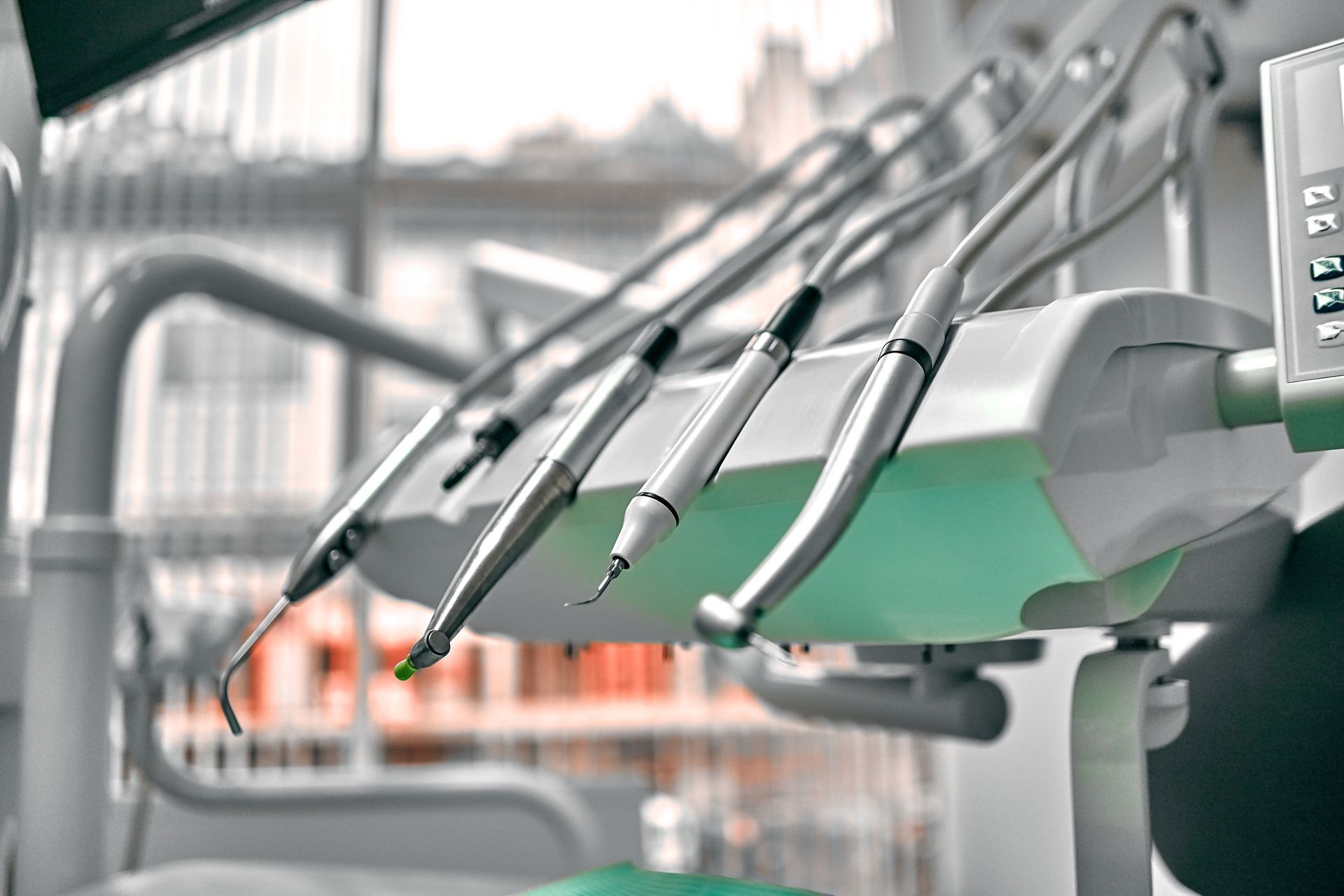 Dental clinic with a row of metal dental tools over a green chair
