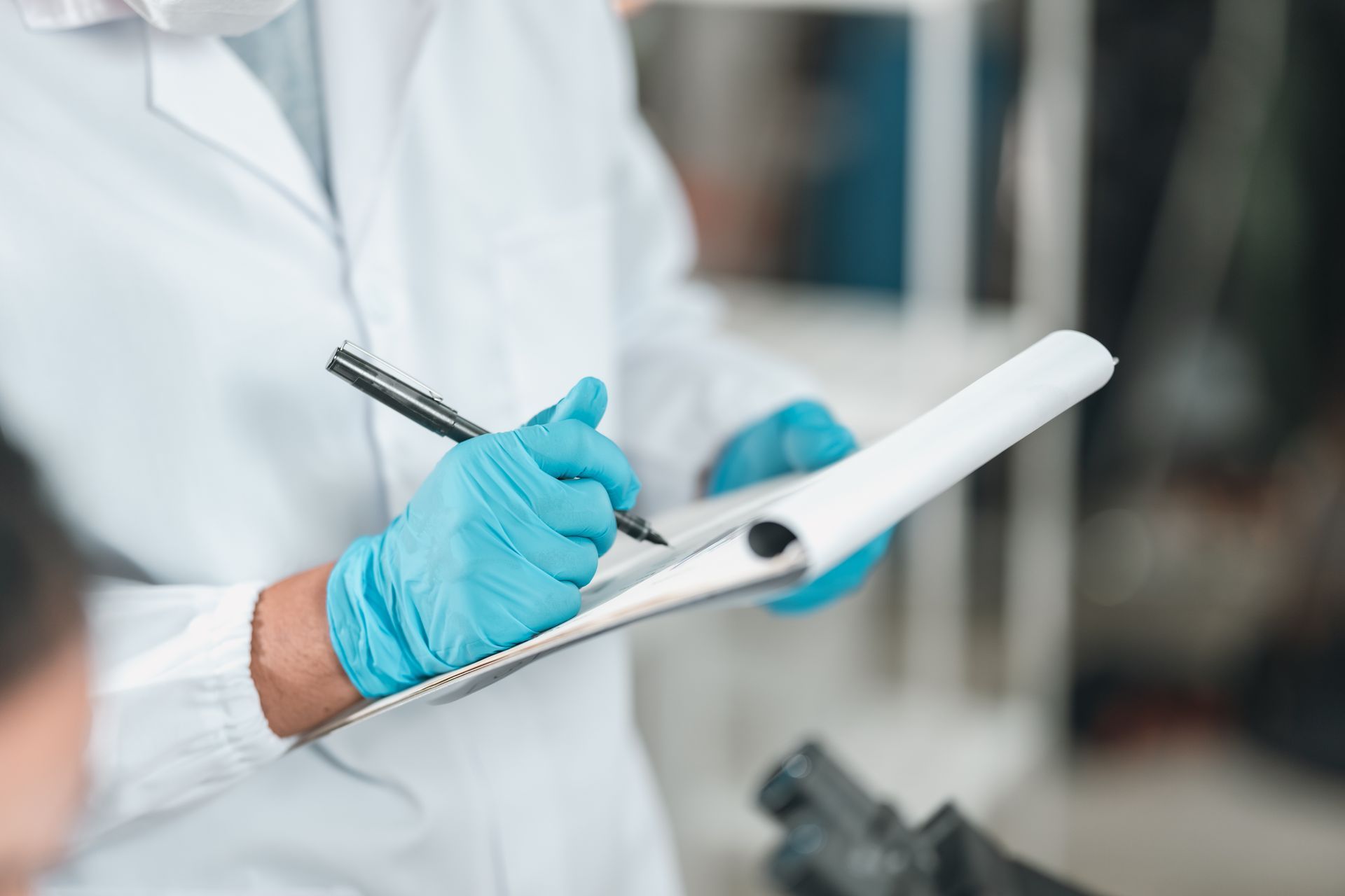 Technician in blue gloves adjusting controls on a wall-mounted medical device