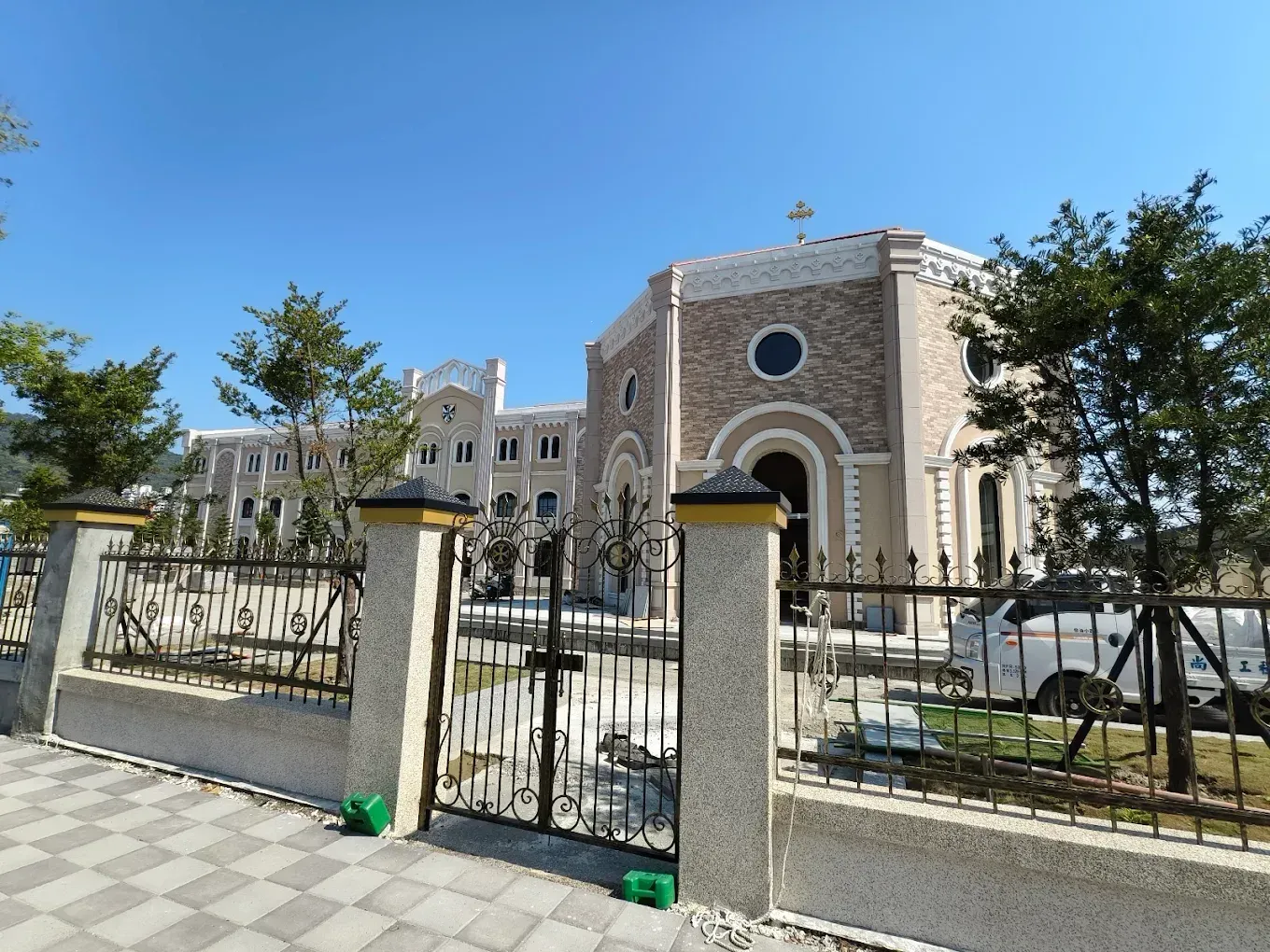 在陽光明媚的日子裡，教堂建築矗立在鍛鐵柵欄後。