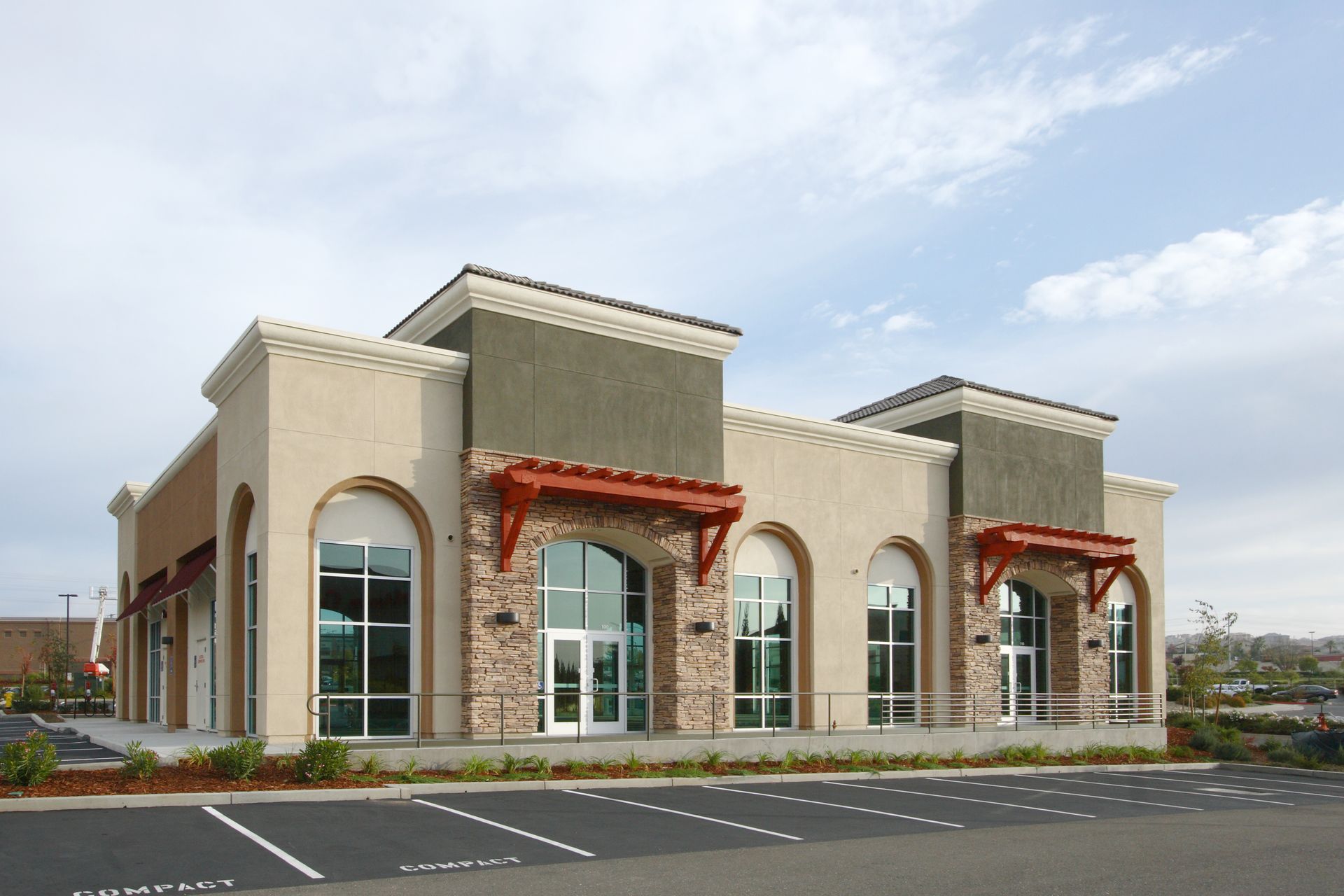 A modern commercial retail strip center with tan stucco walls.