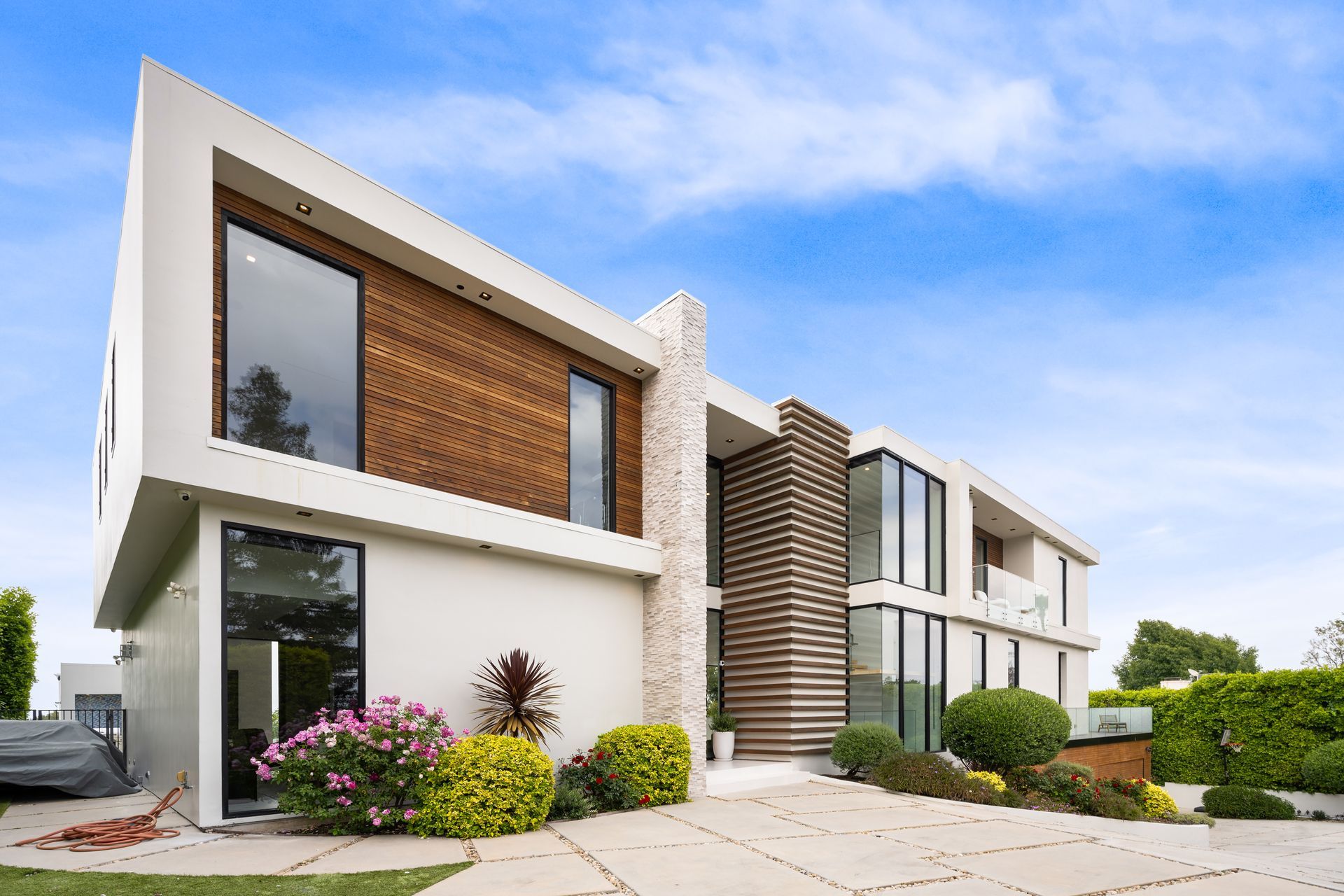 A modern, two-story house with white walls, wood-slat siding.