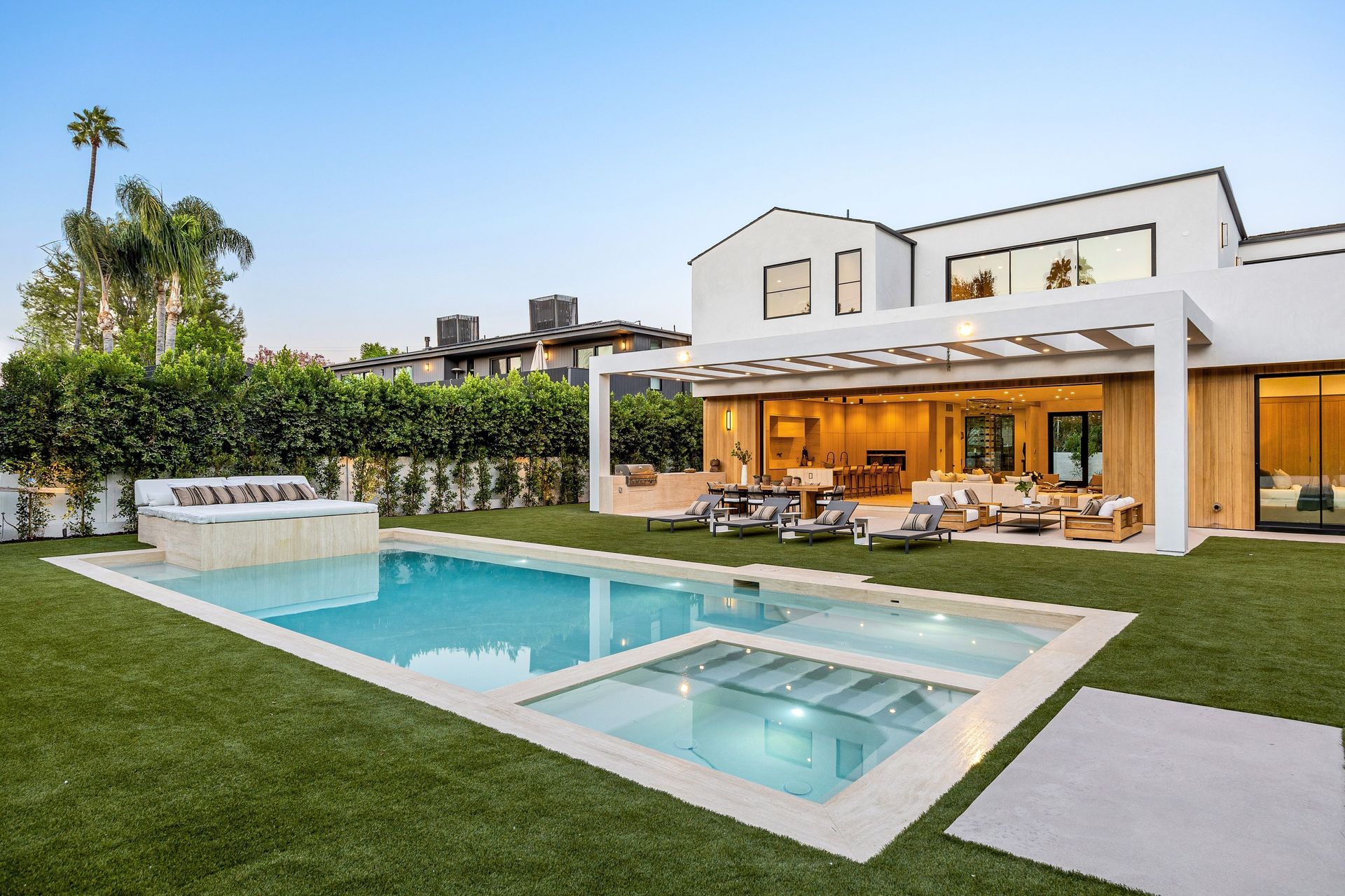 A modern white house with a pool, spa, and patio area.