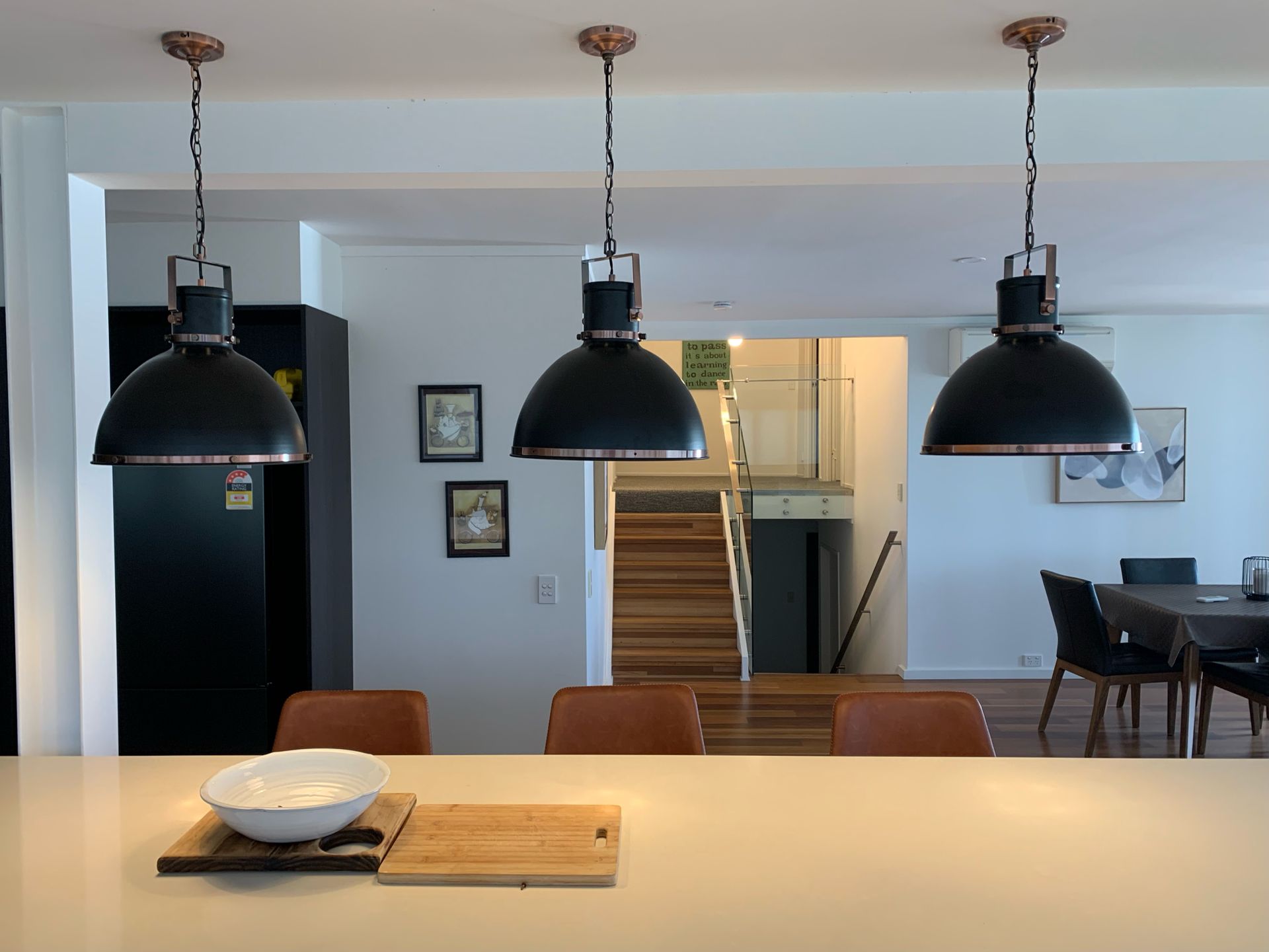 A kitchen with three black pendant lights hanging from the ceiling