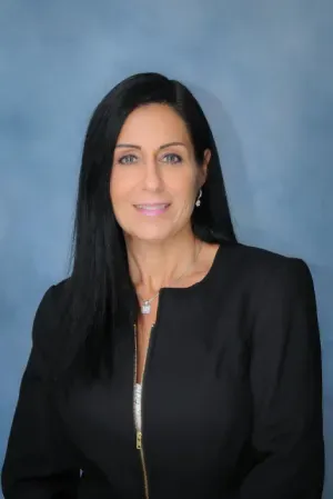 Portrait of a smiling woman in a black blazer against a blue background