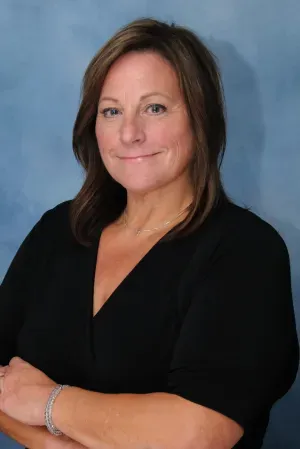 Portrait of a woman in a black top against a blue studio backdrop