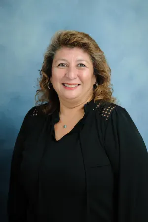 Smiling woman in a black top against a blue studio backdrop