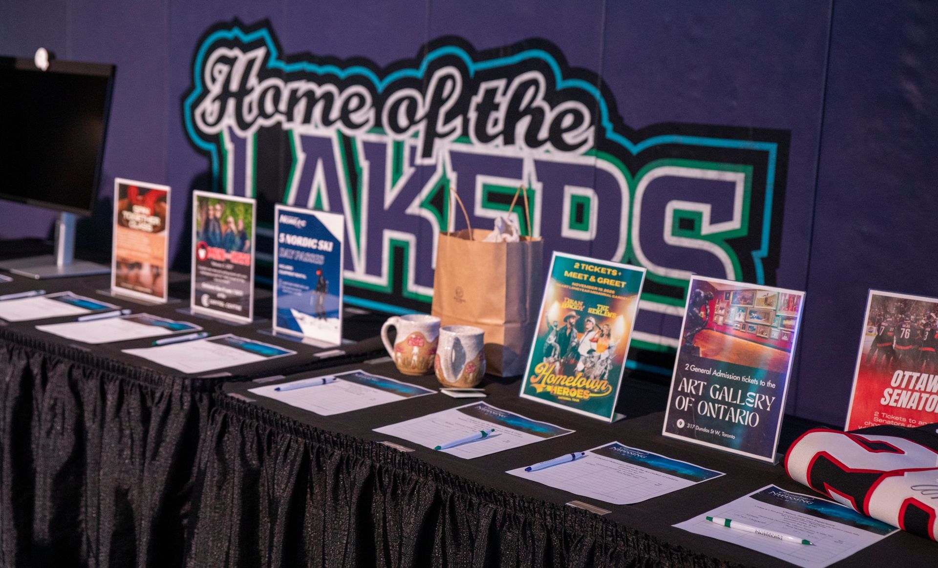 Table with books and display signs in front of a “Home of the LAKERS” banner on a purple wall