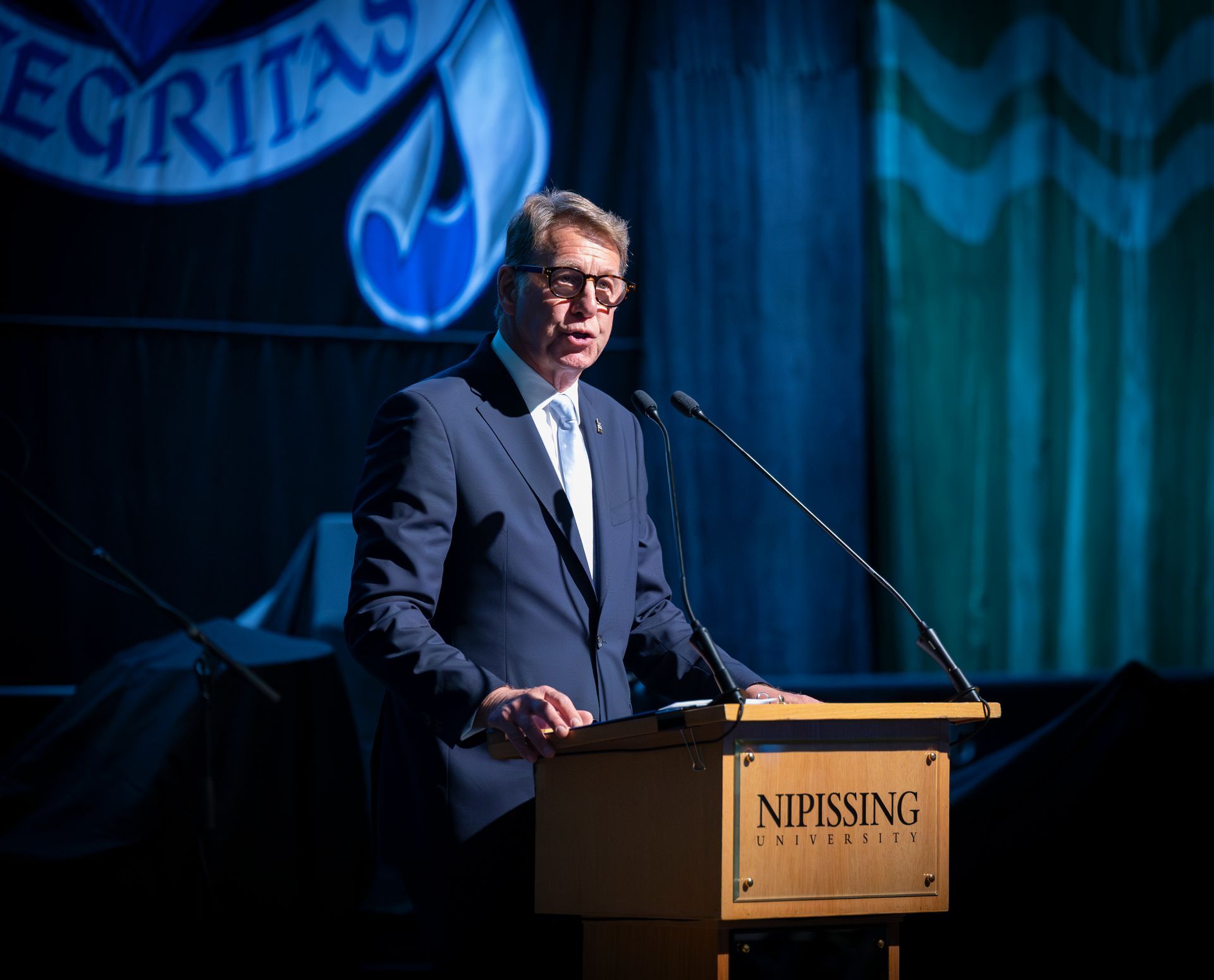 Scott Russell is giving a speech on stage at Evening at Nipissing 2026