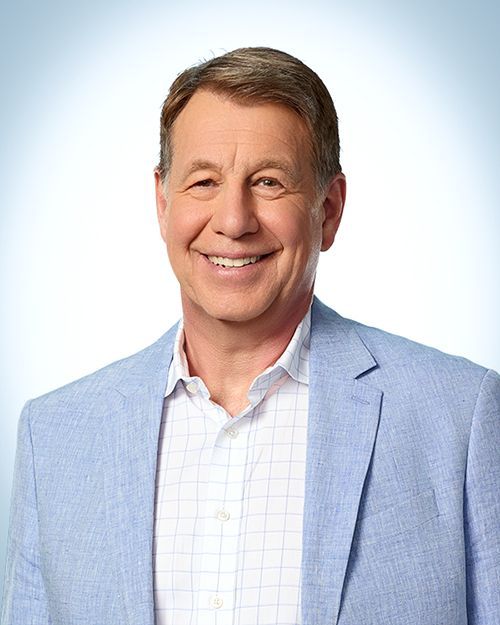 Scott Russel in a light blue blazer and white shirt against a pale blue background