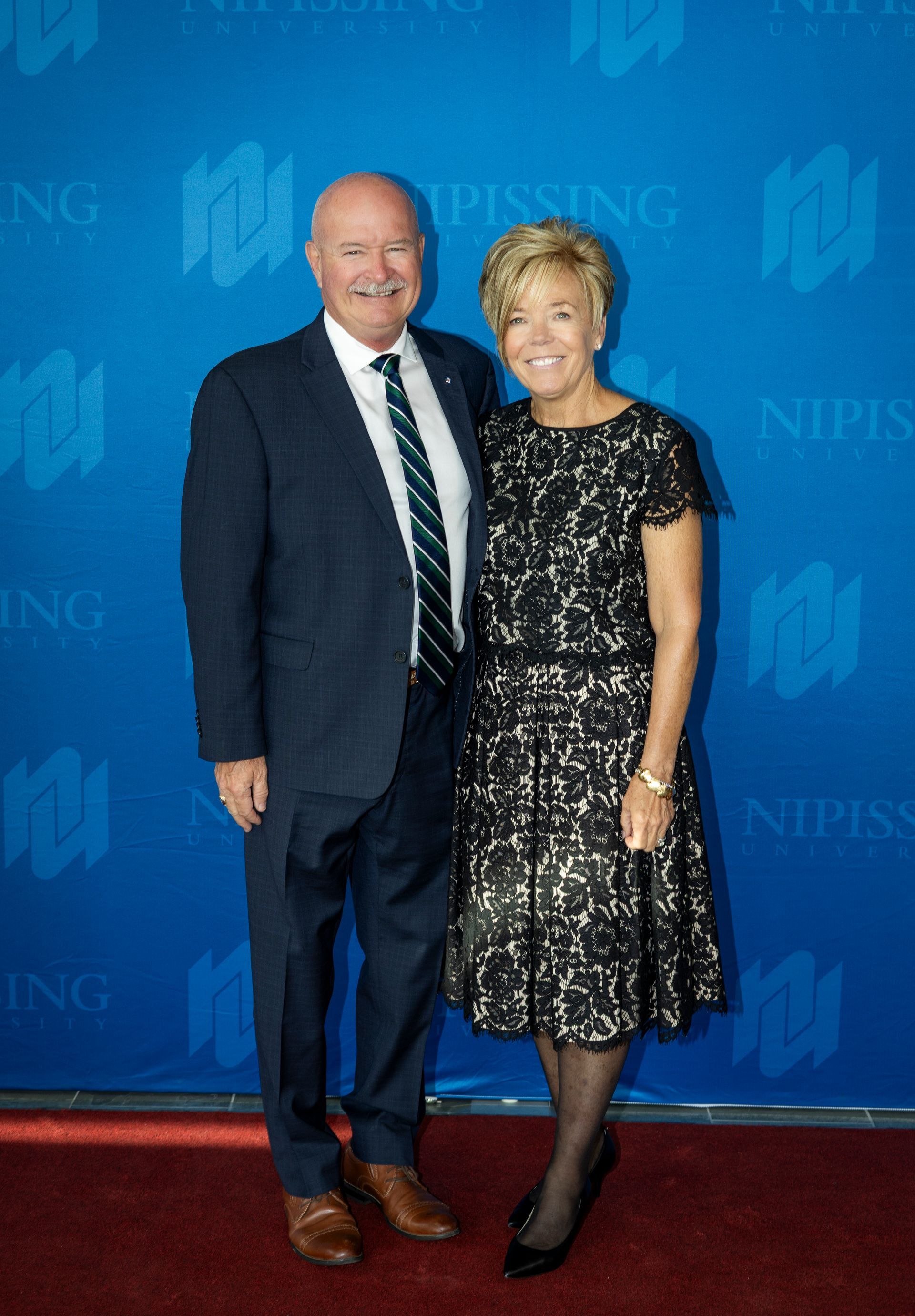 Evening at Nipissing 2026 attendees smiling against Nipissing University backdrop 