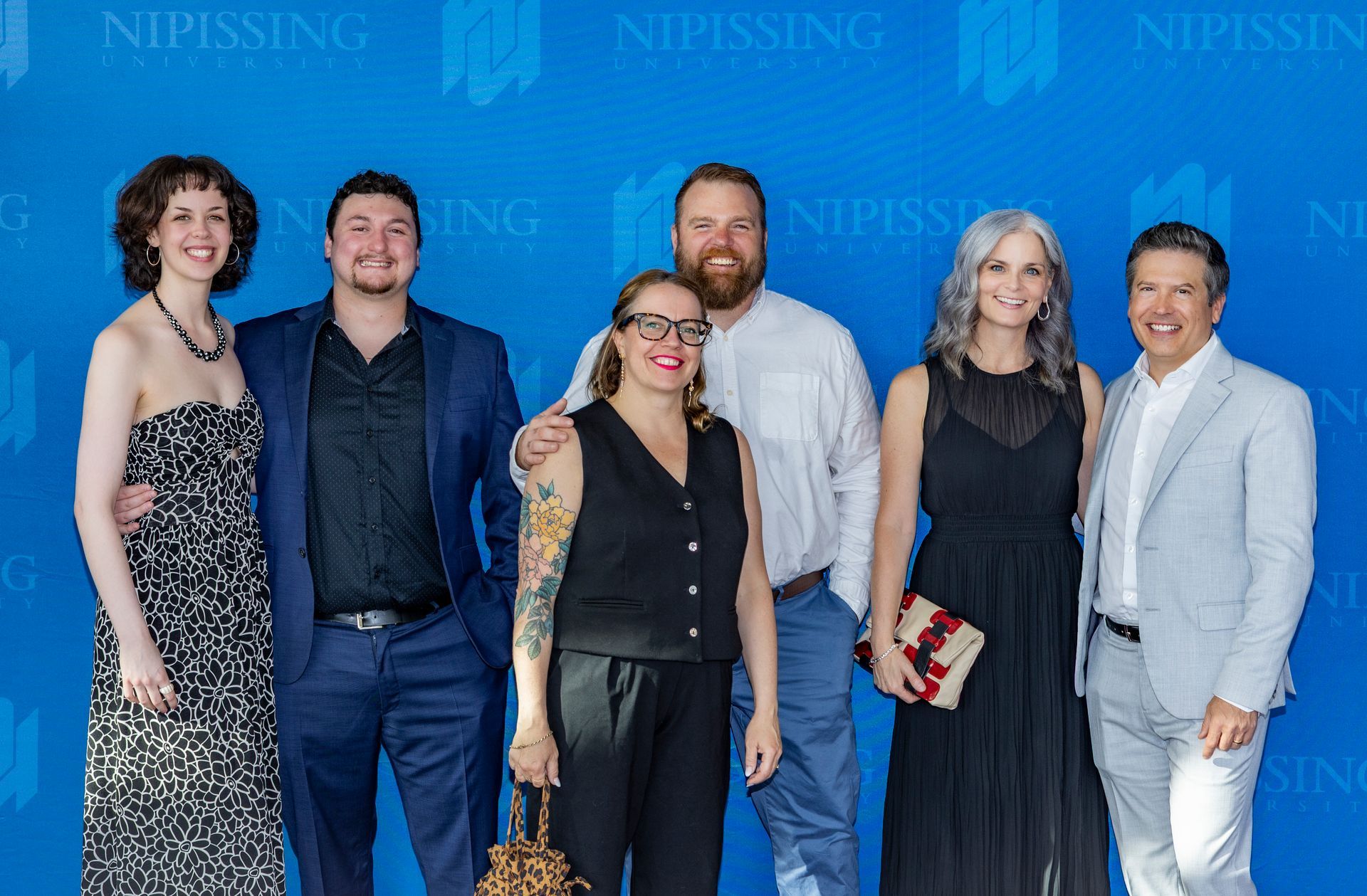 Evening at Nipissing 2026 attendees smiling against Nipissing University backdrop 