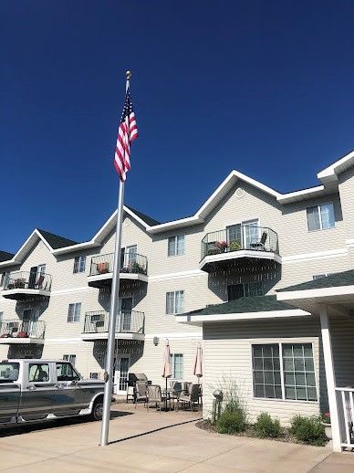 An American flag flies in front of a multi-story building with balconies on a sunny day.