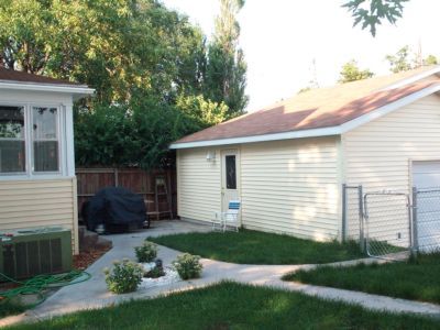 Backyard with a yellow house and garage.  A black car cover and green grass are visible.