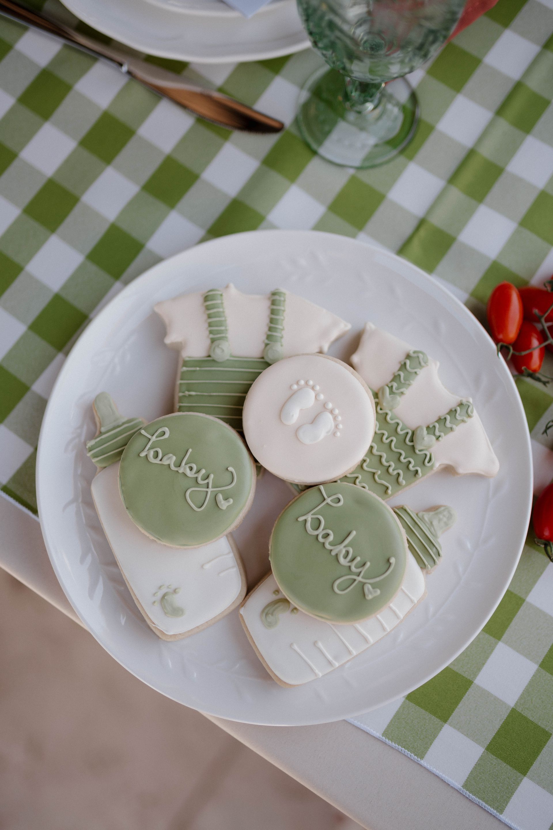 A white plate topped with green and white cookies on a table.