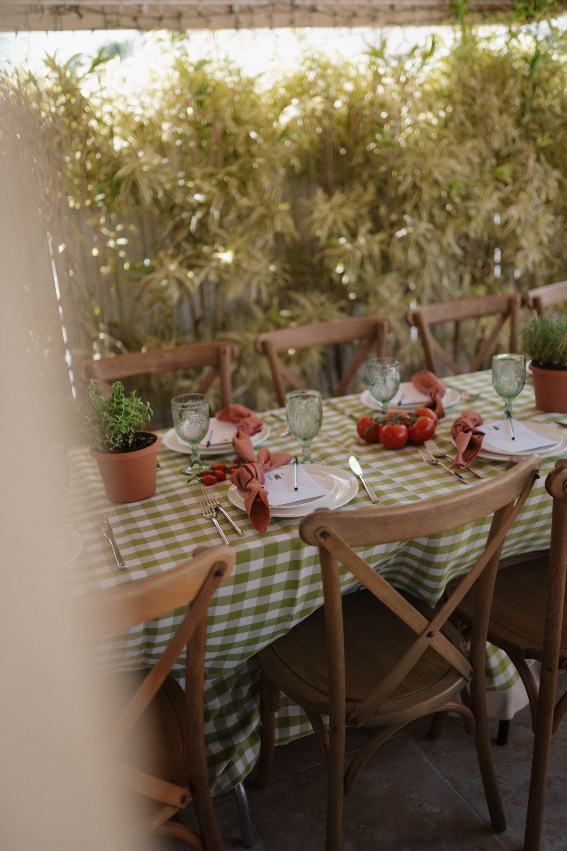 A table with plates, glasses, and tomatoes on it.