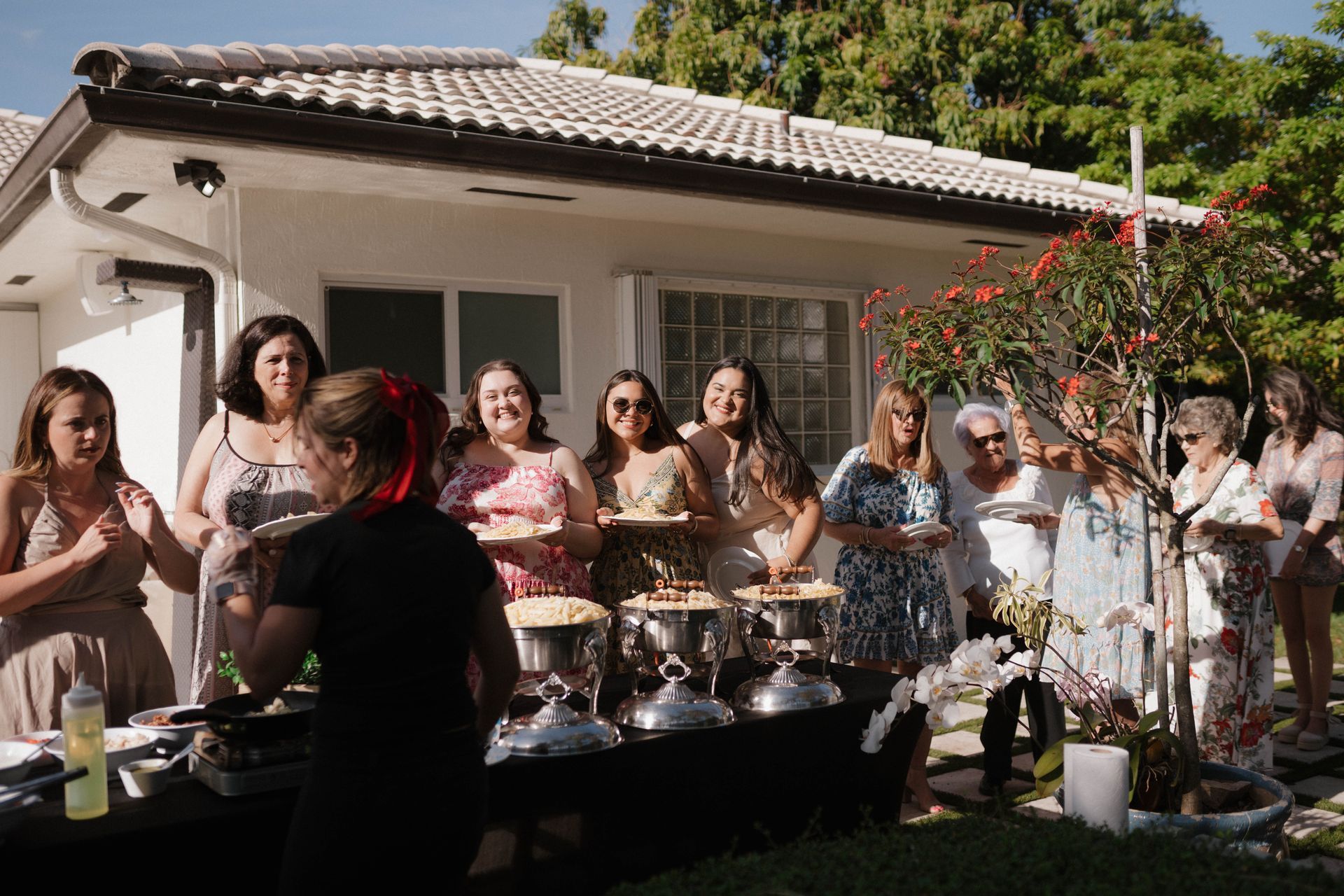 A group of women are standing around a table in front of a house.