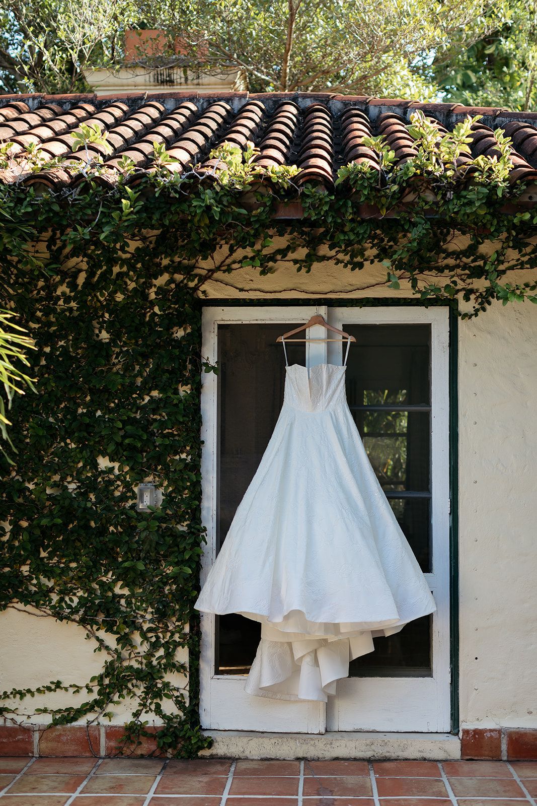 A wedding dress is hanging on a door in front of a building.