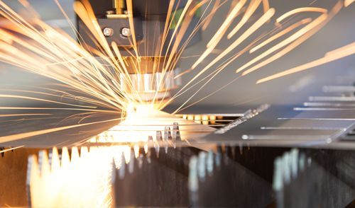 A machine is cutting a piece of metal with sparks coming out of it.