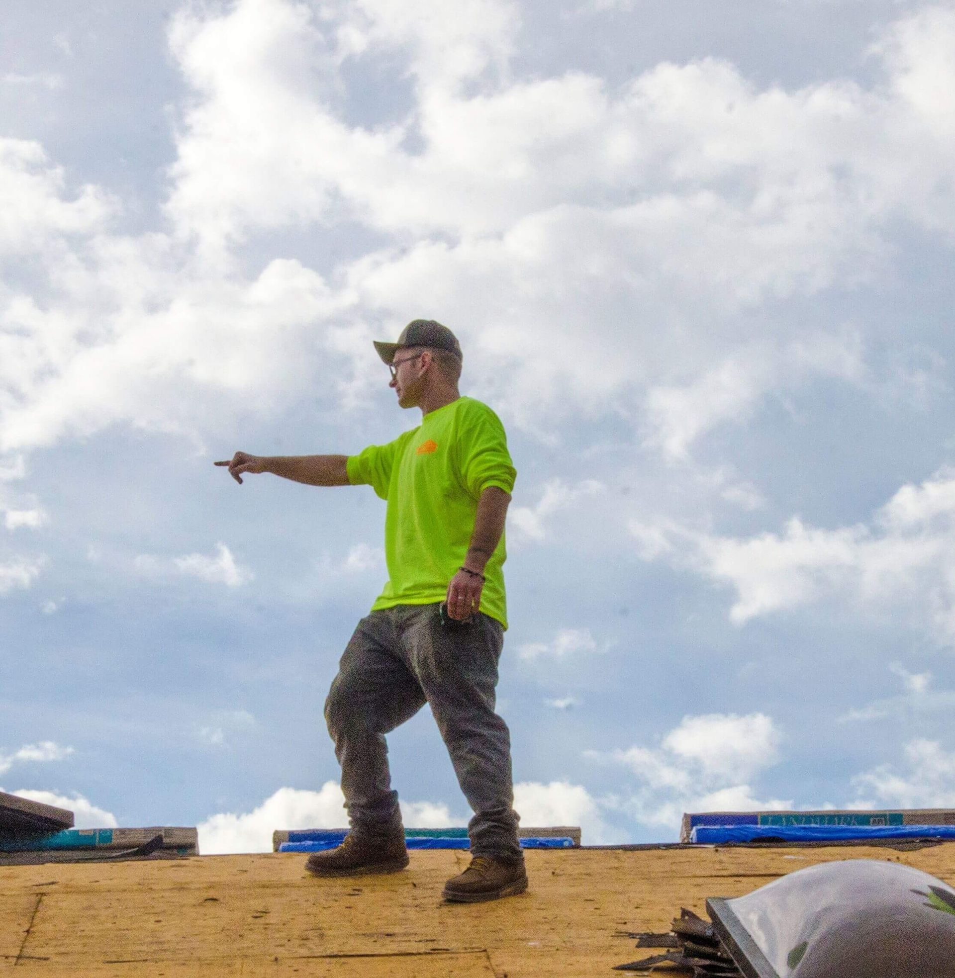 photo of a man in yellow on top of a residential roof installation project