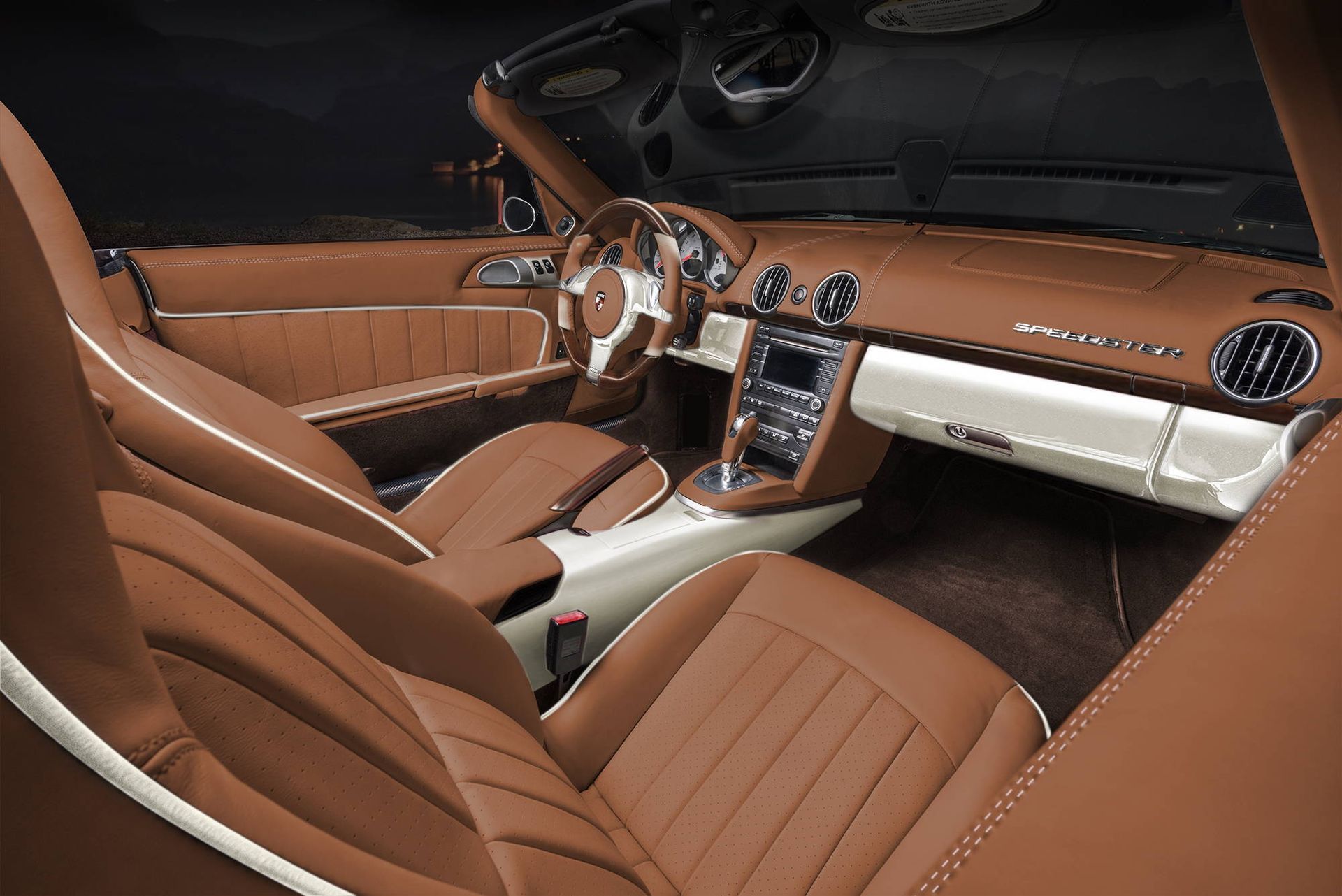 Luxury car interior with tan leather seats, wood trim, and a silver center console at night