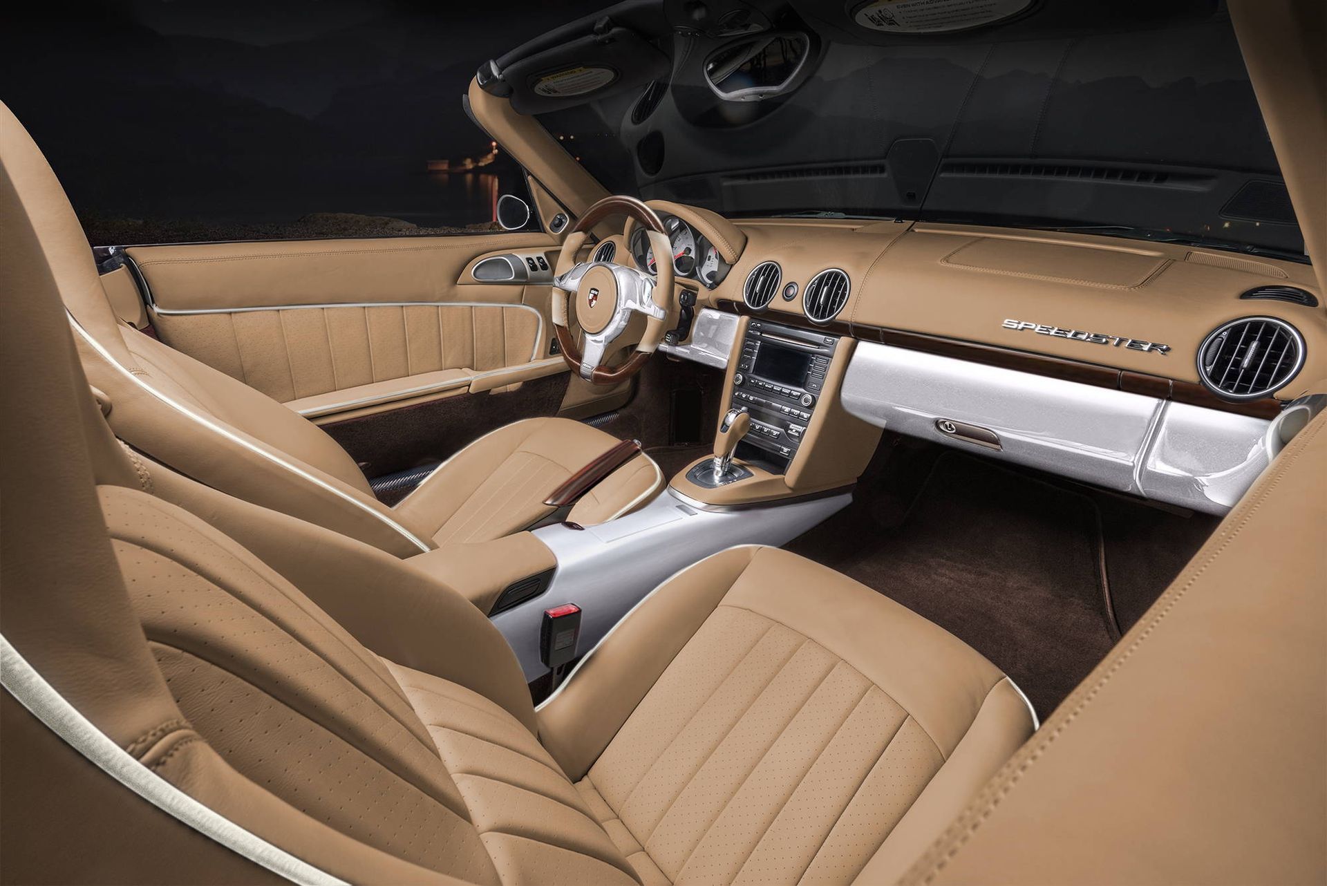 Tan luxury sports car interior with tan leather seats, silver dashboard, and center console
