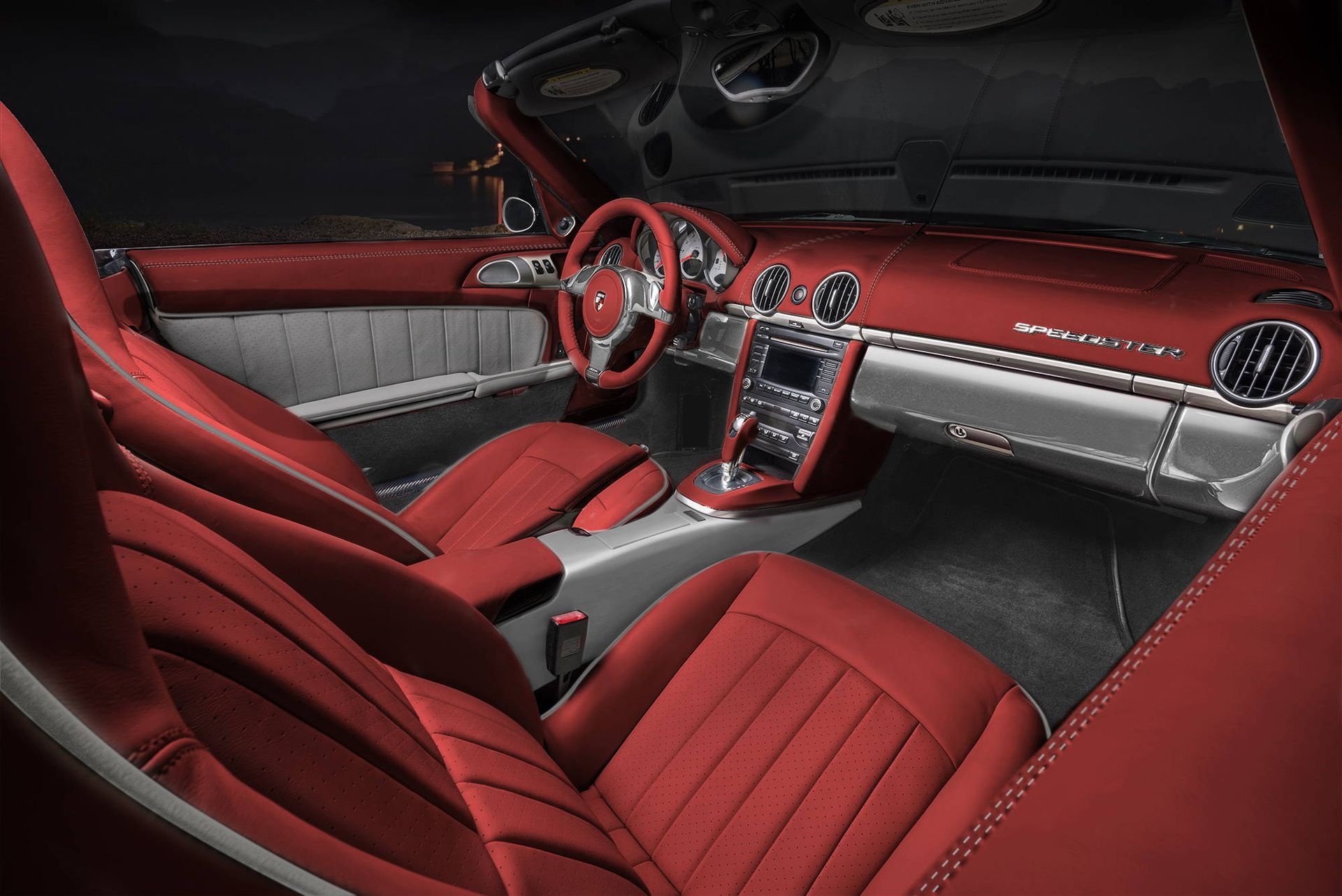 Luxury car interior with red leather seats, silver dashboard trim, and center console on display.