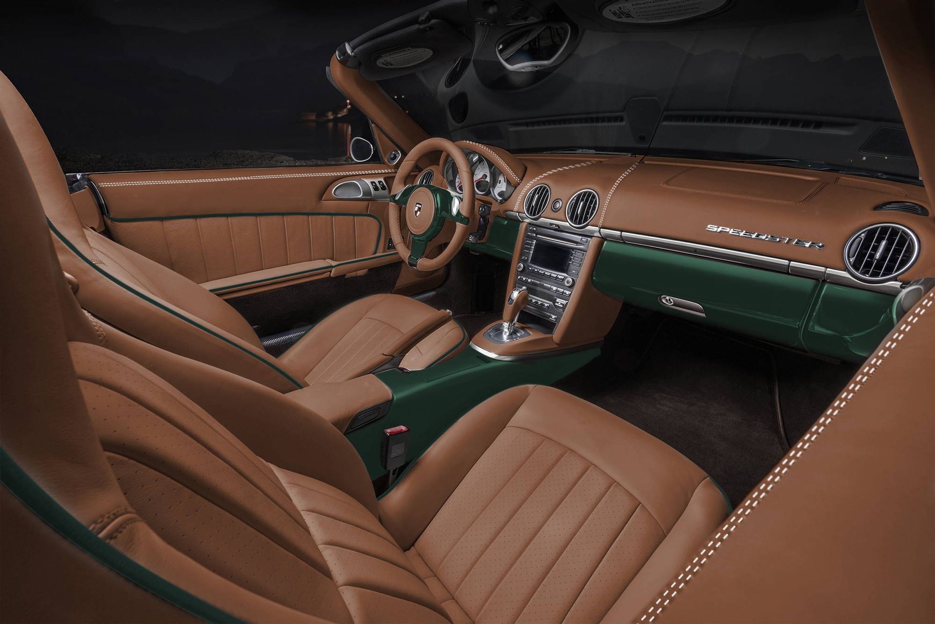 Luxury car interior with brown leather seats, green dashboard trim, and wood steering wheel at night